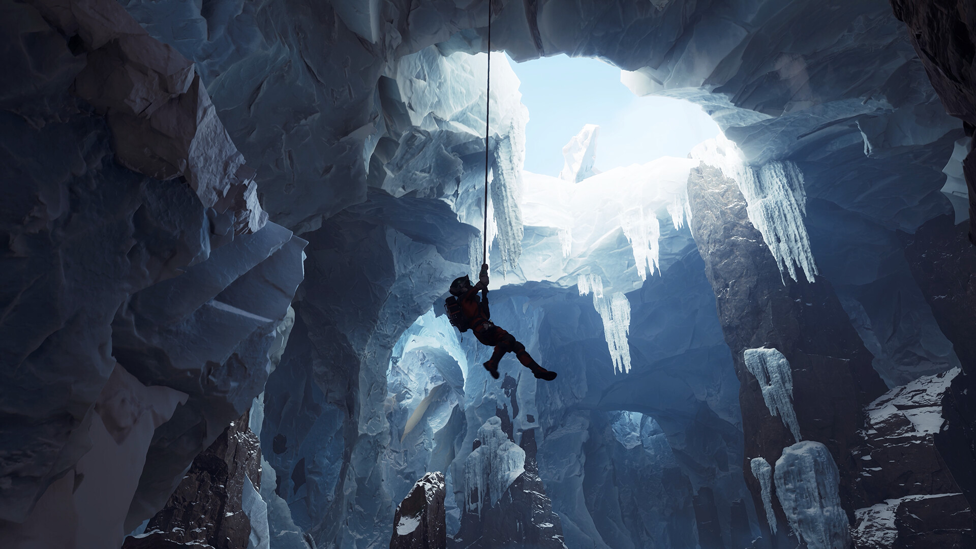 Un grimpeur descend en rappel dans une grotte glacée, entouré de formations de glace.