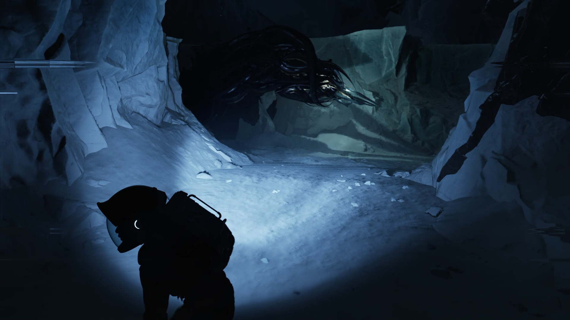 Un astronaute dans une grotte glacée éclaire une créature sombre et tentaculaire avec une lampe torche.