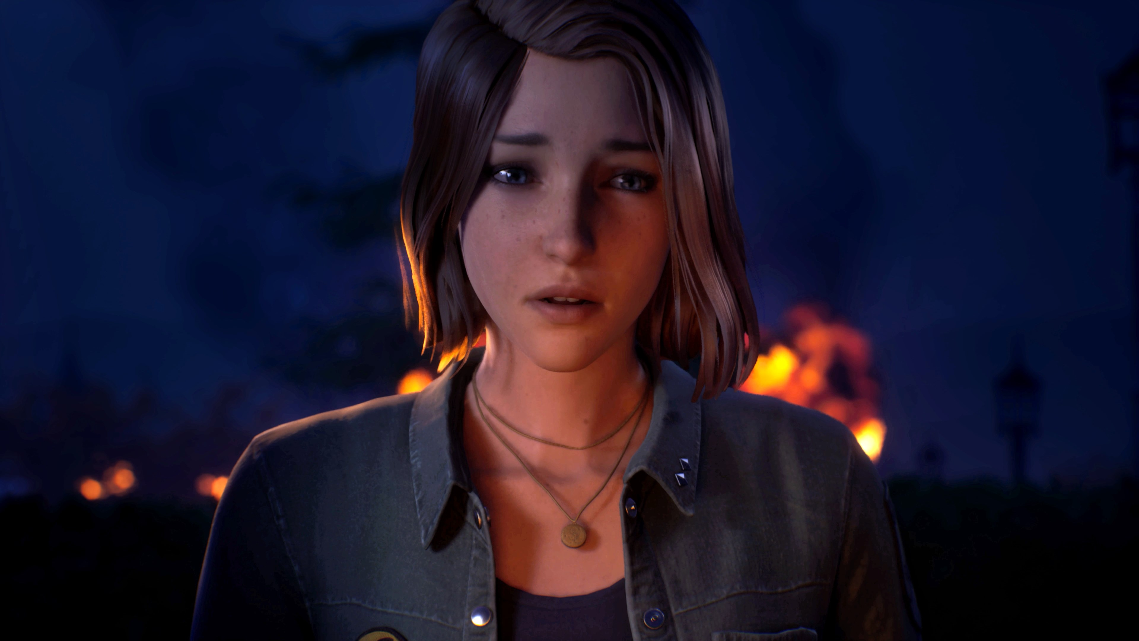 Jeune femme aux cheveux bruns devant un fond nocturne avec des flammes.