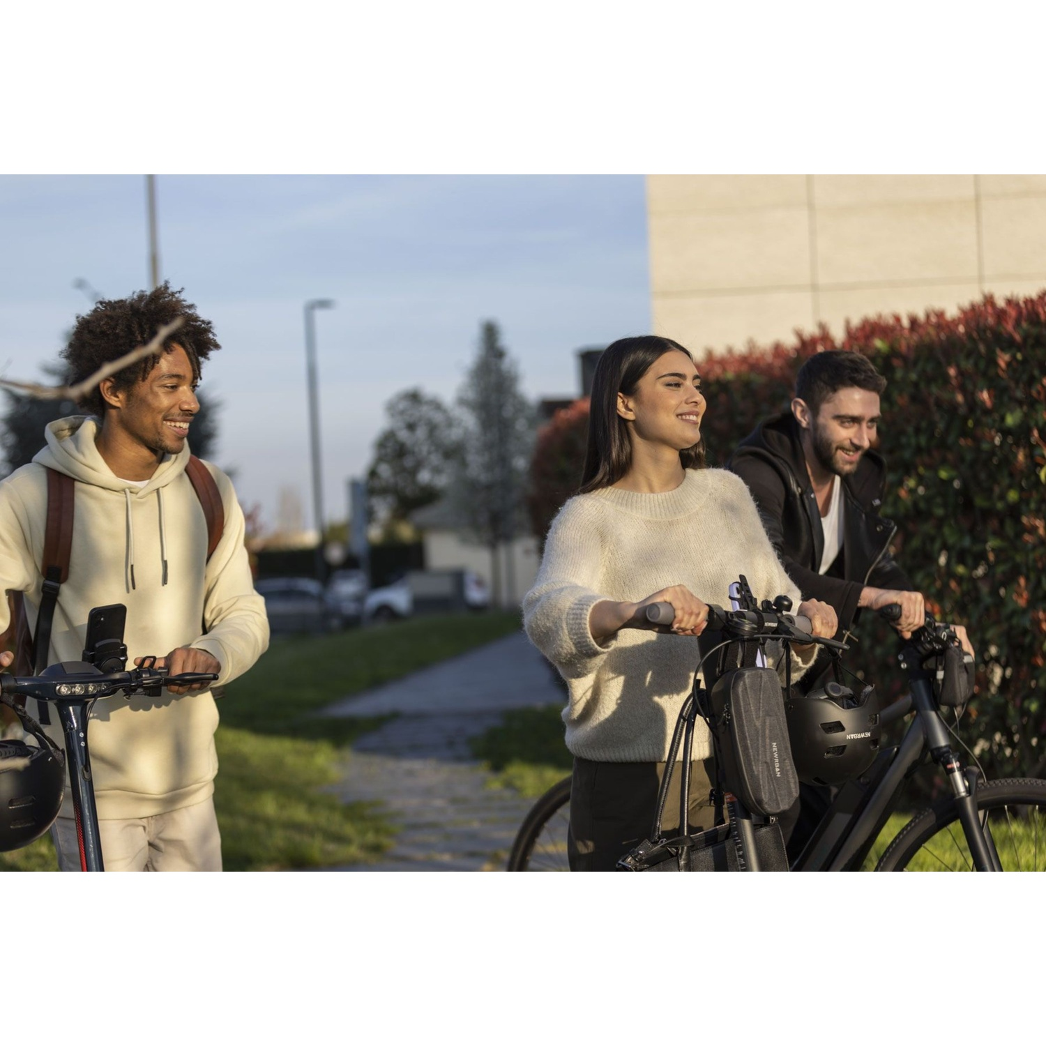 Tre persone vanno in monopattino e in bicicletta all'aperto.