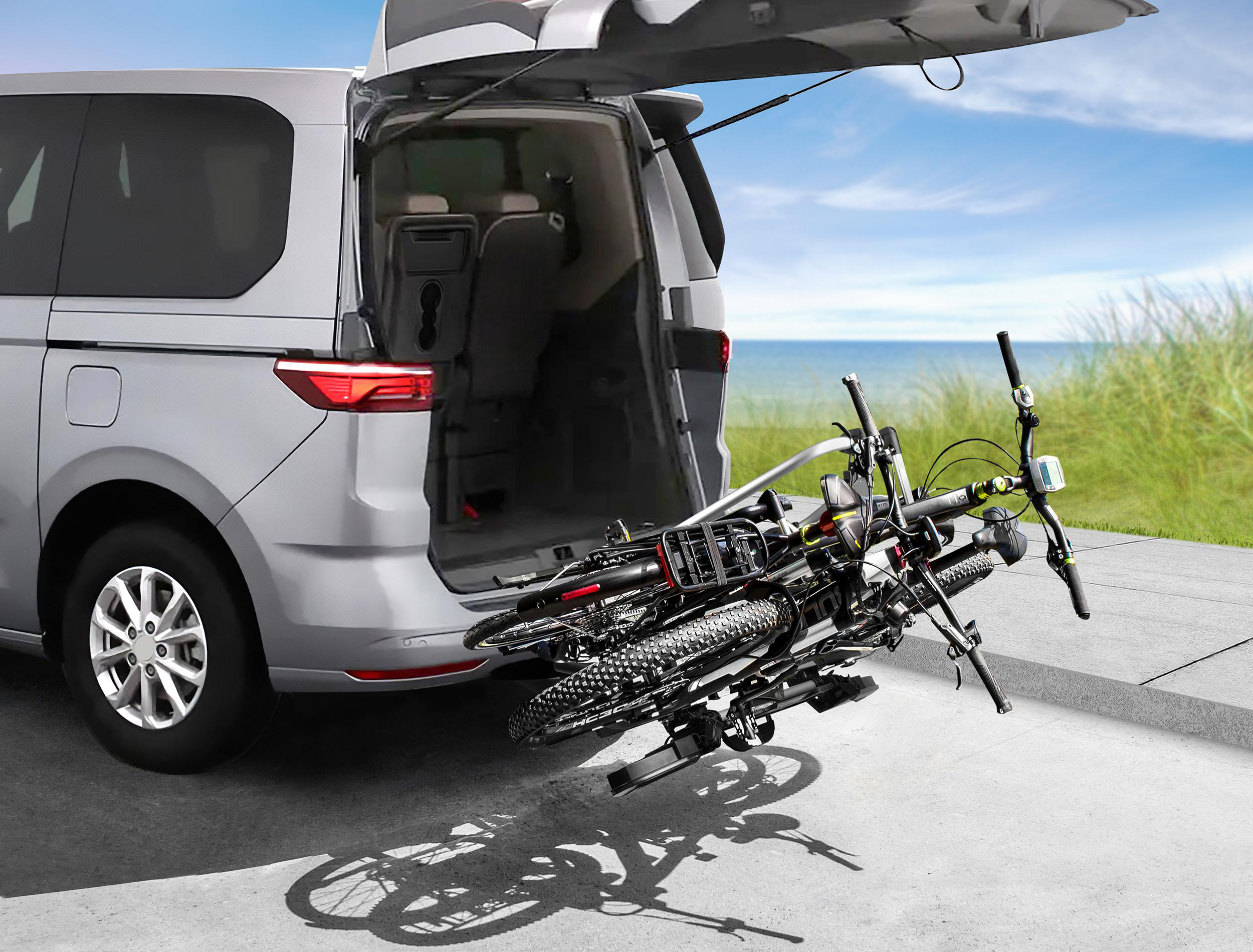 Silbernes Auto mit geöffneter Heckklappe und Fahrrädern auf einem Fahrradträger.