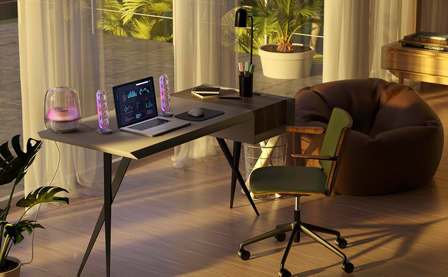 Ein Schreibtisch mit Laptop, Lautsprechern und Lampe vor einem Fenster.