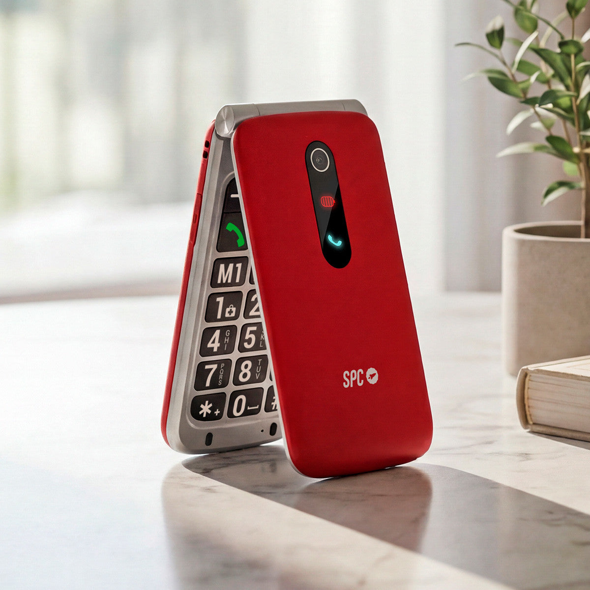 Un teléfono plegable rojo con botones grandes descansa sobre una mesa.