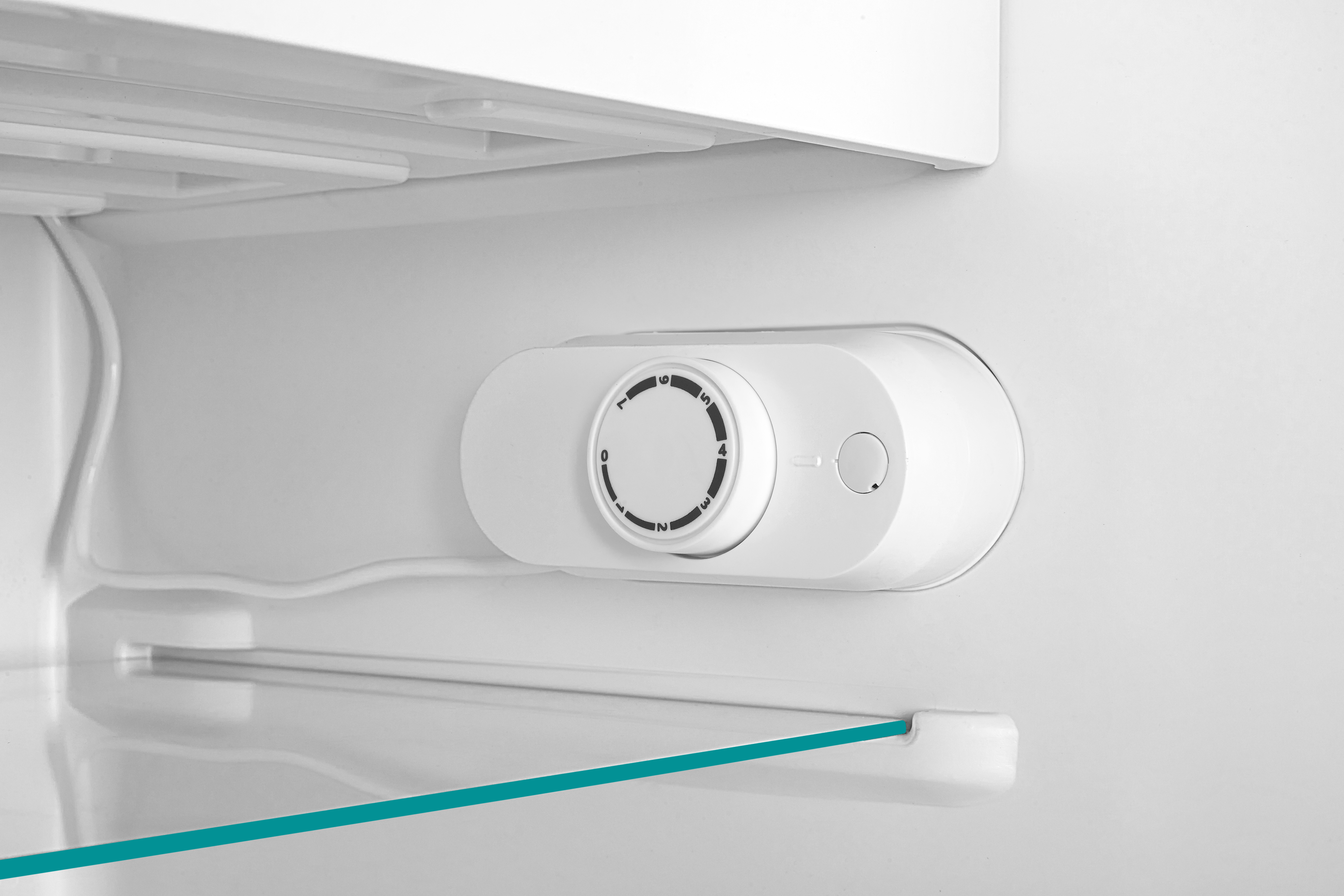 Un termostato blanco con dial de 0 a 7 dentro de un refrigerador.