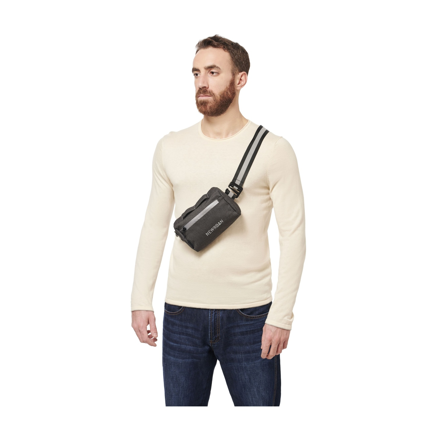 Un uomo con la barba indossa un maglione color crema, jeans e una borsa grigia a tracolla.