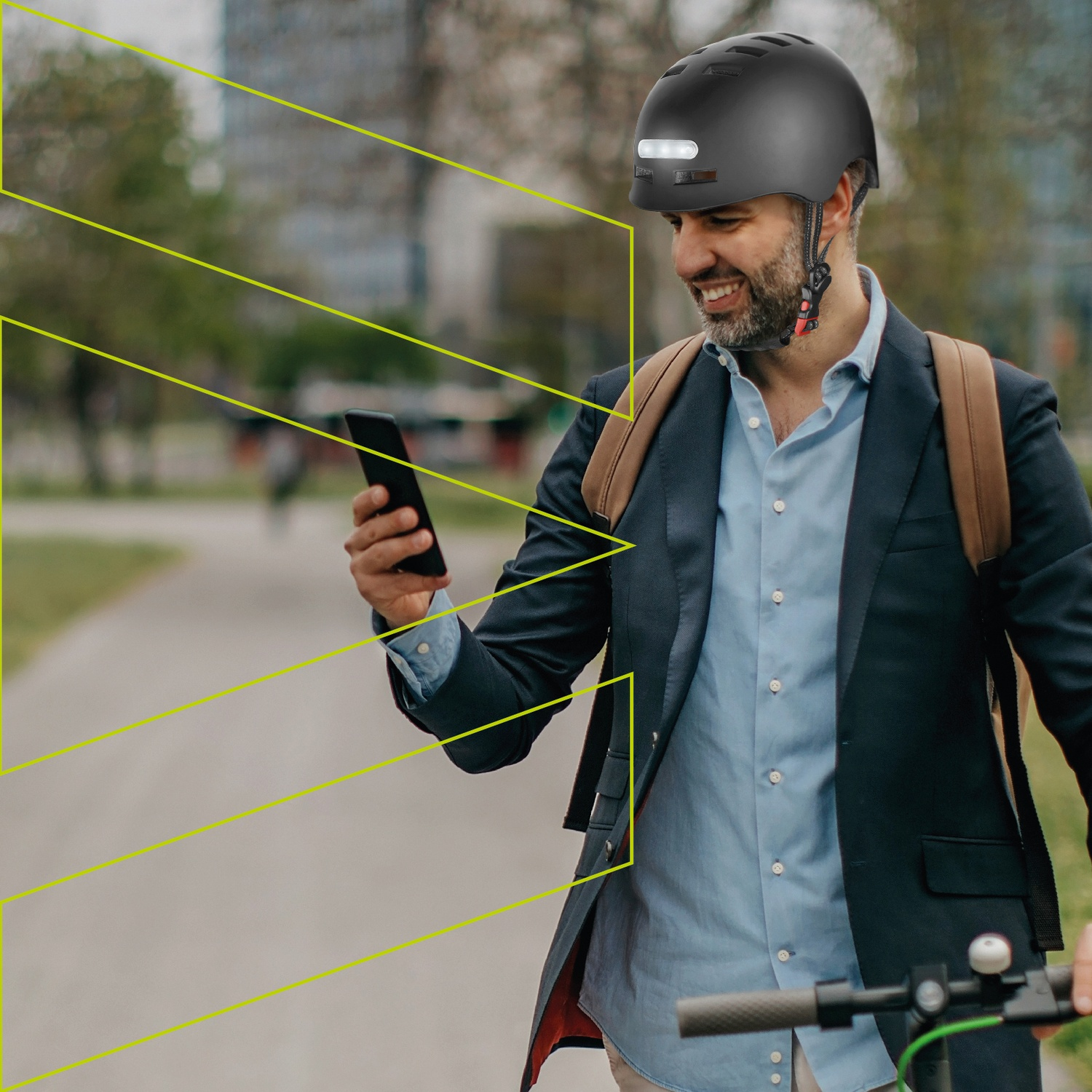 Un uomo in giacca e cravatta, con casco e zaino, guarda il telefono.