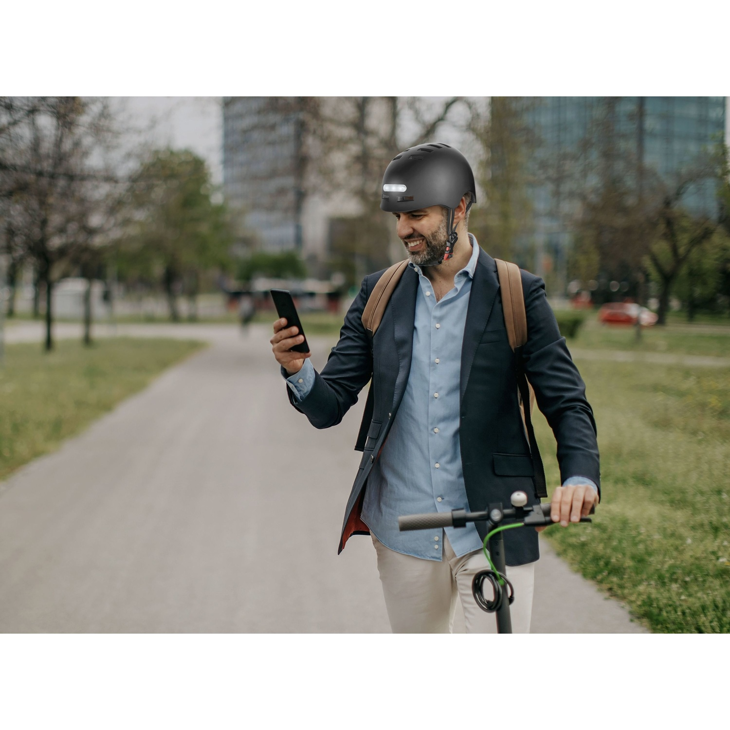 Uomo con casco e telefono su monopattino elettrico.