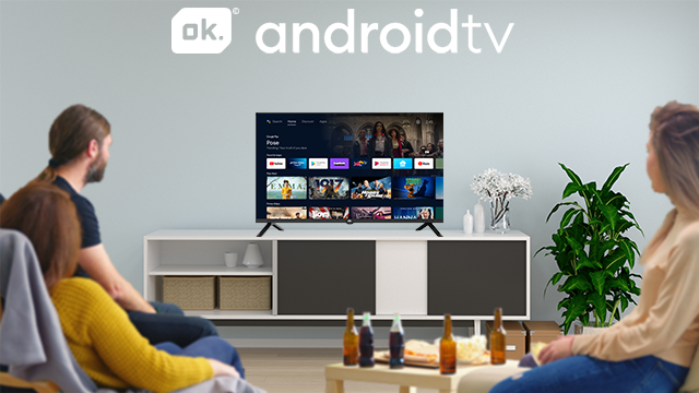 Cztery osoby oglądają telewizję. Ok. Android TV wyświetla aplikacje. Butelki stoją na stole.