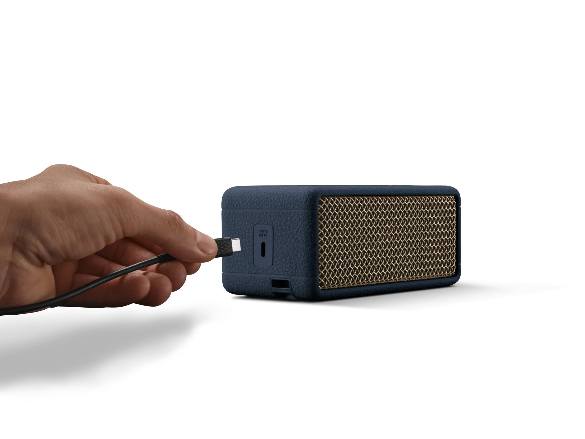 Bir el, altın ızgaralı mavi bir hoparlöre USB kablosu takıyor.