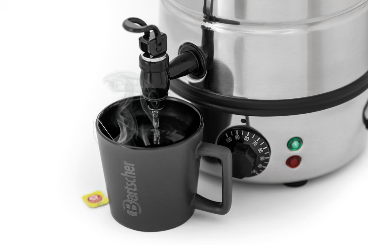 Heißes Wasser fließt aus einem Zapfhahn in eine dunkle Tasse mit einem Teebeutel.
