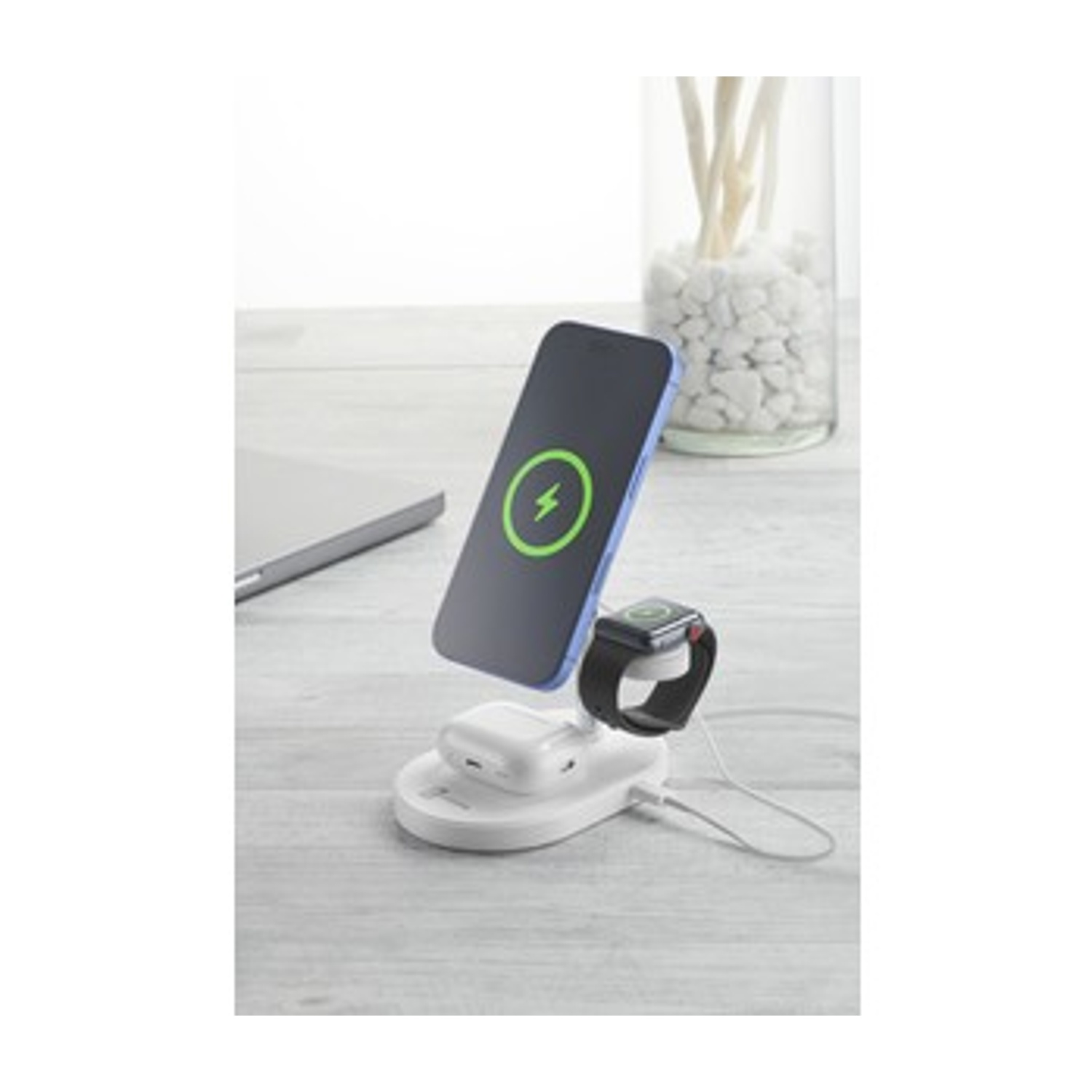 Un iPhone, Apple Watch e AirPods in carica su una stazione di ricarica bianca.