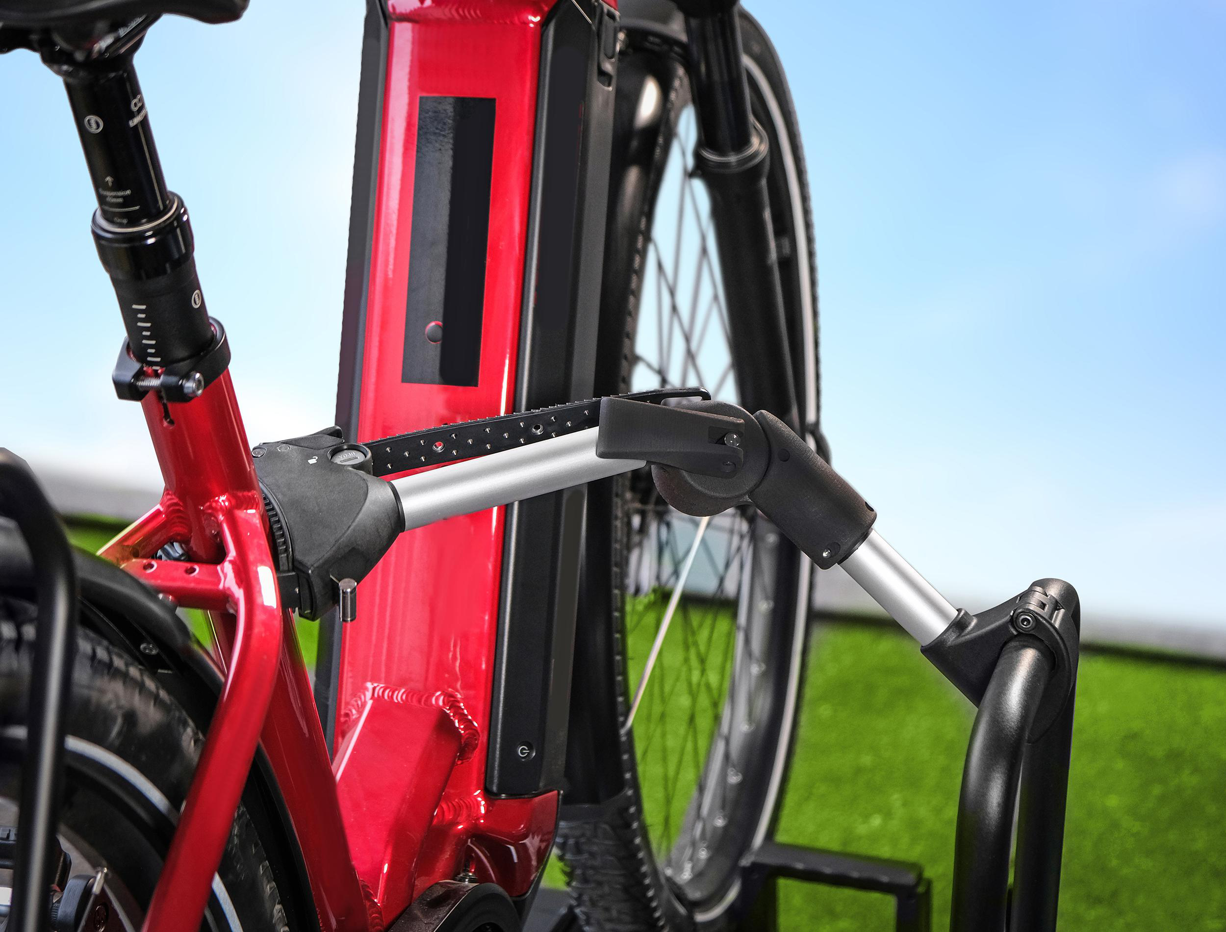 Nahaufnahme eines roten E-Bikes mit schwarzem Akku und Reifen, blauer Himmel.