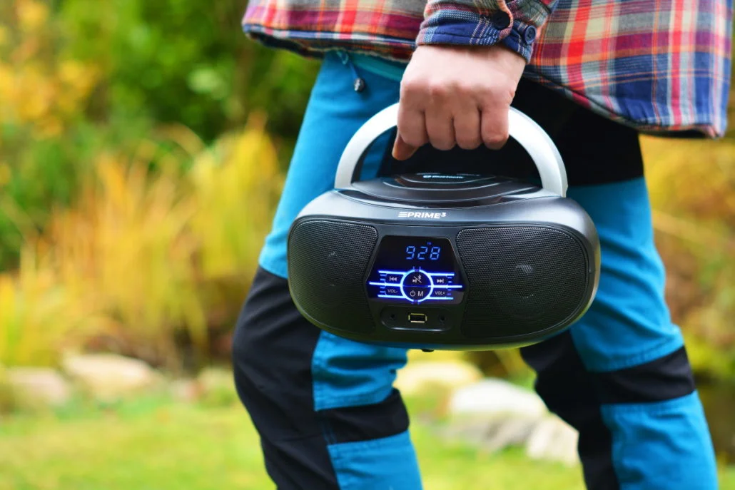 Osoba trzyma czarny przenośny odtwarzacz CD z uchwytem na zewnątrz.