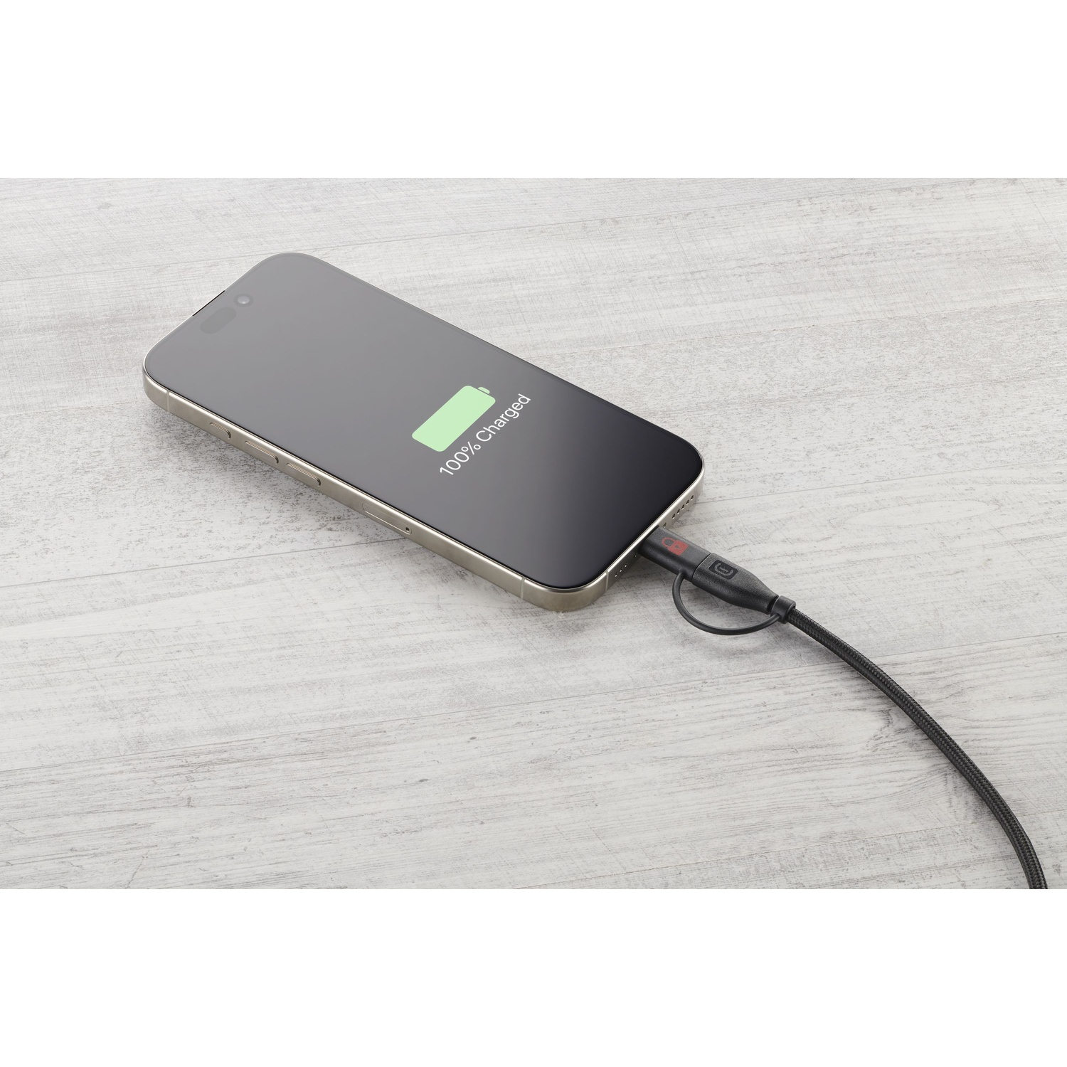 Uno smartphone mostra 100% di carica, collegato a un cavo di ricarica nero.