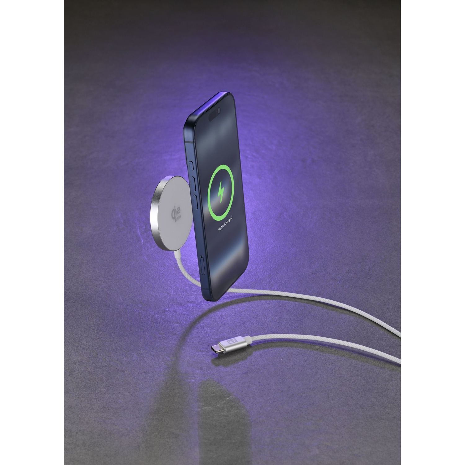 Un telefono blu scuro si carica magneticamente su un pad bianco. Un cavo bianco si collega al telefono.