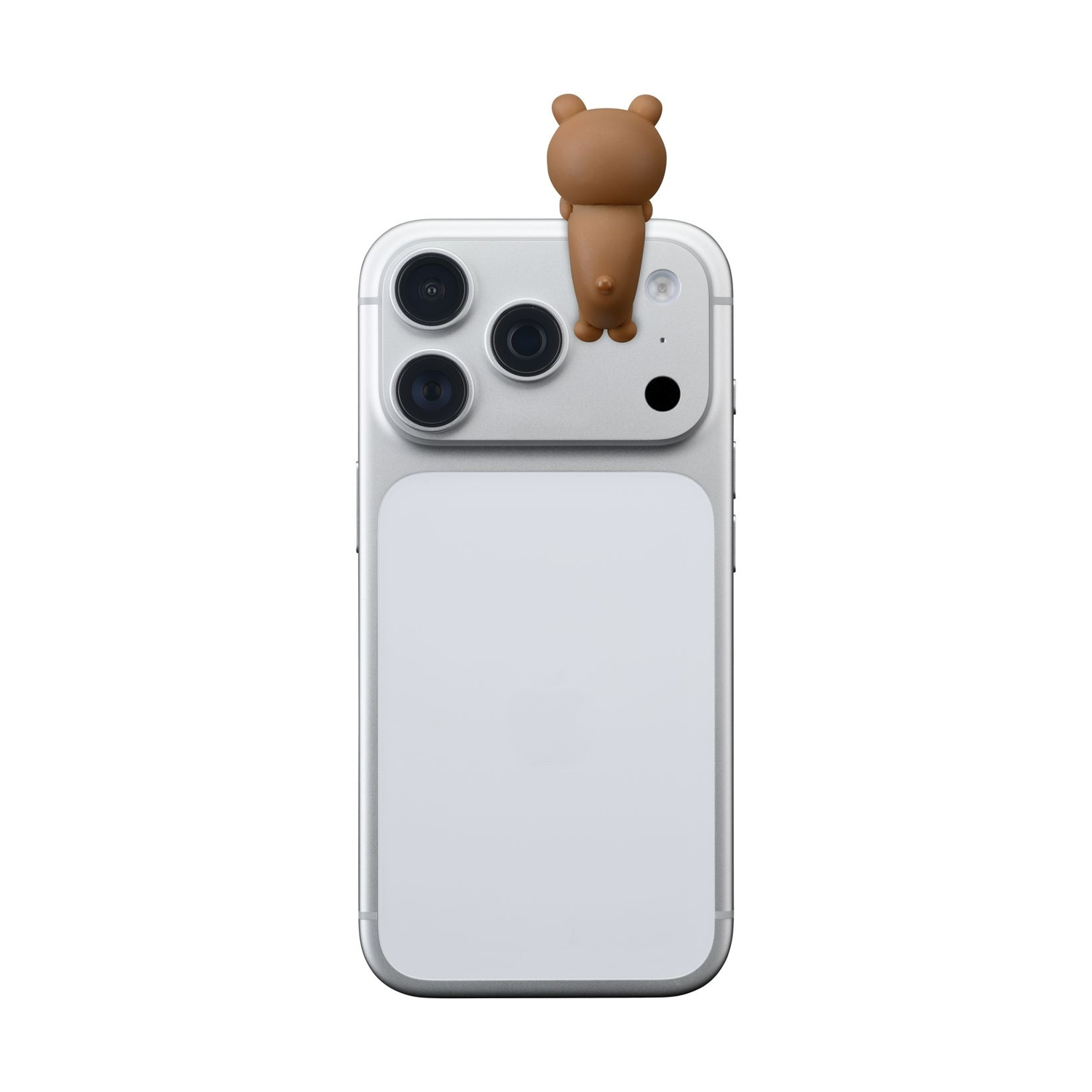 Un ciondolo a forma di orso marrone siede sul retro di un iPhone argentato con tre fotocamere.