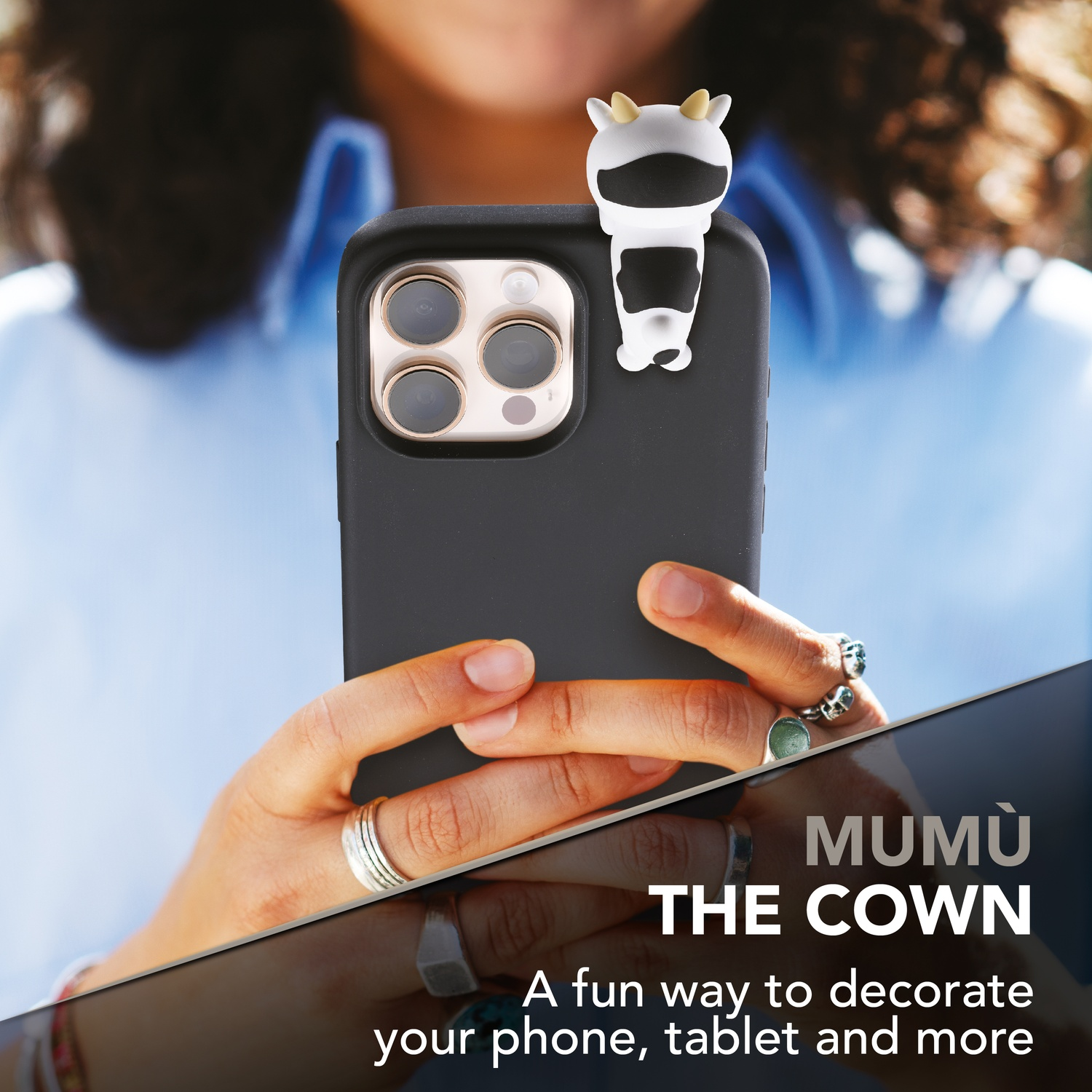 Una persona tiene uno smartphone con una figura di mucca. Testo: MUMU THE COWN.