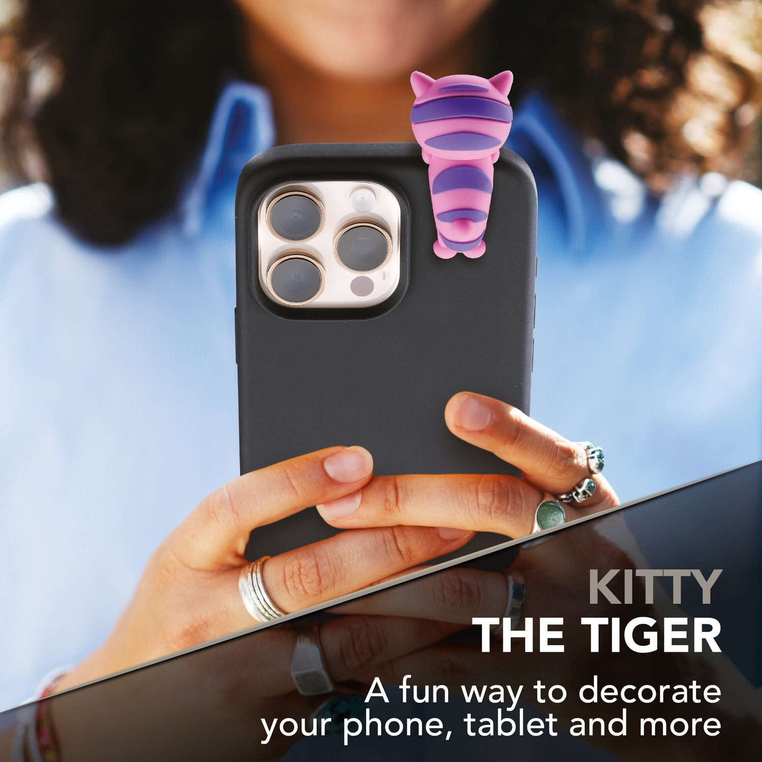 Una clip a tigre rosa e viola su un iPhone nero. Le mani tengono il telefono.