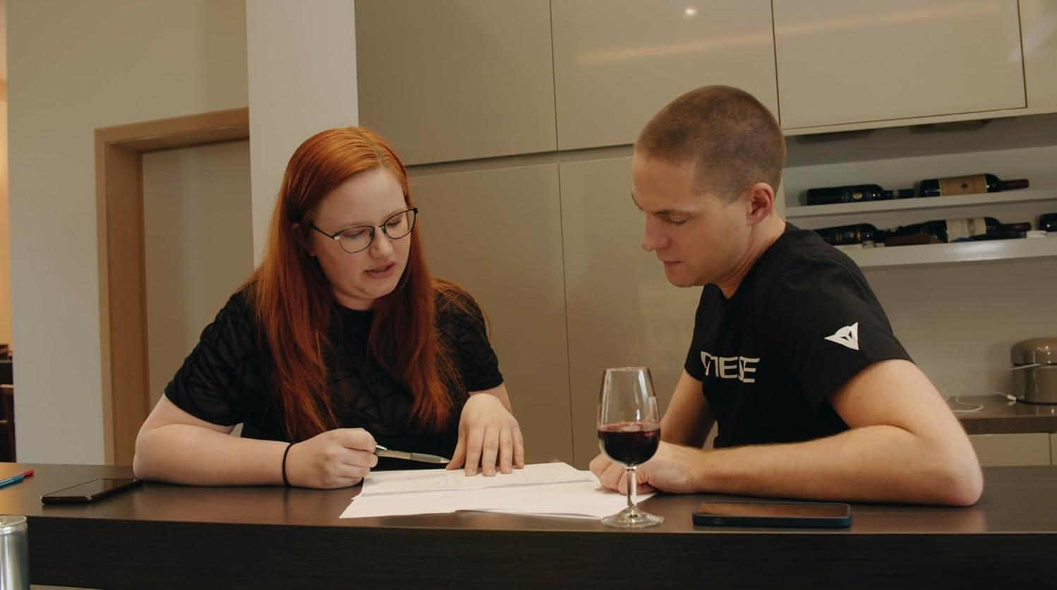 Eine Frau mit roten Haaren und eine Mann mit Glatze besprechen Dokumente.