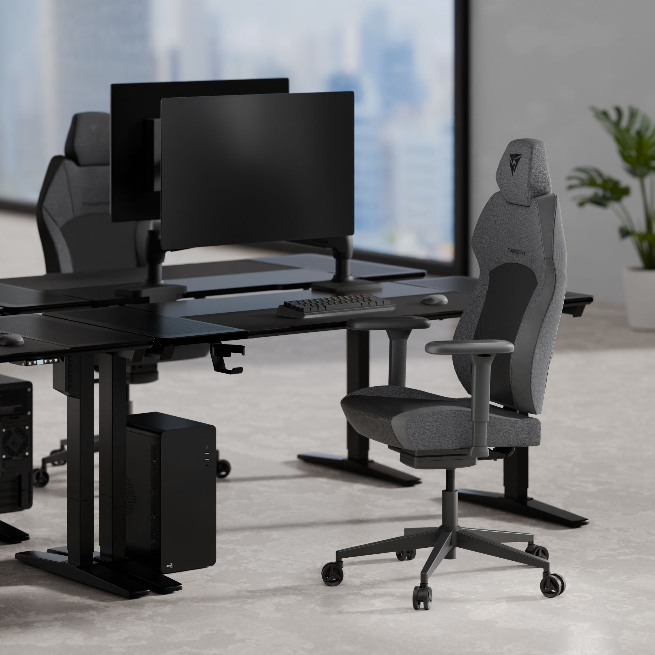 Grauer Gaming-Stuhl vor einem Schreibtisch mit Computern und Monitoren.