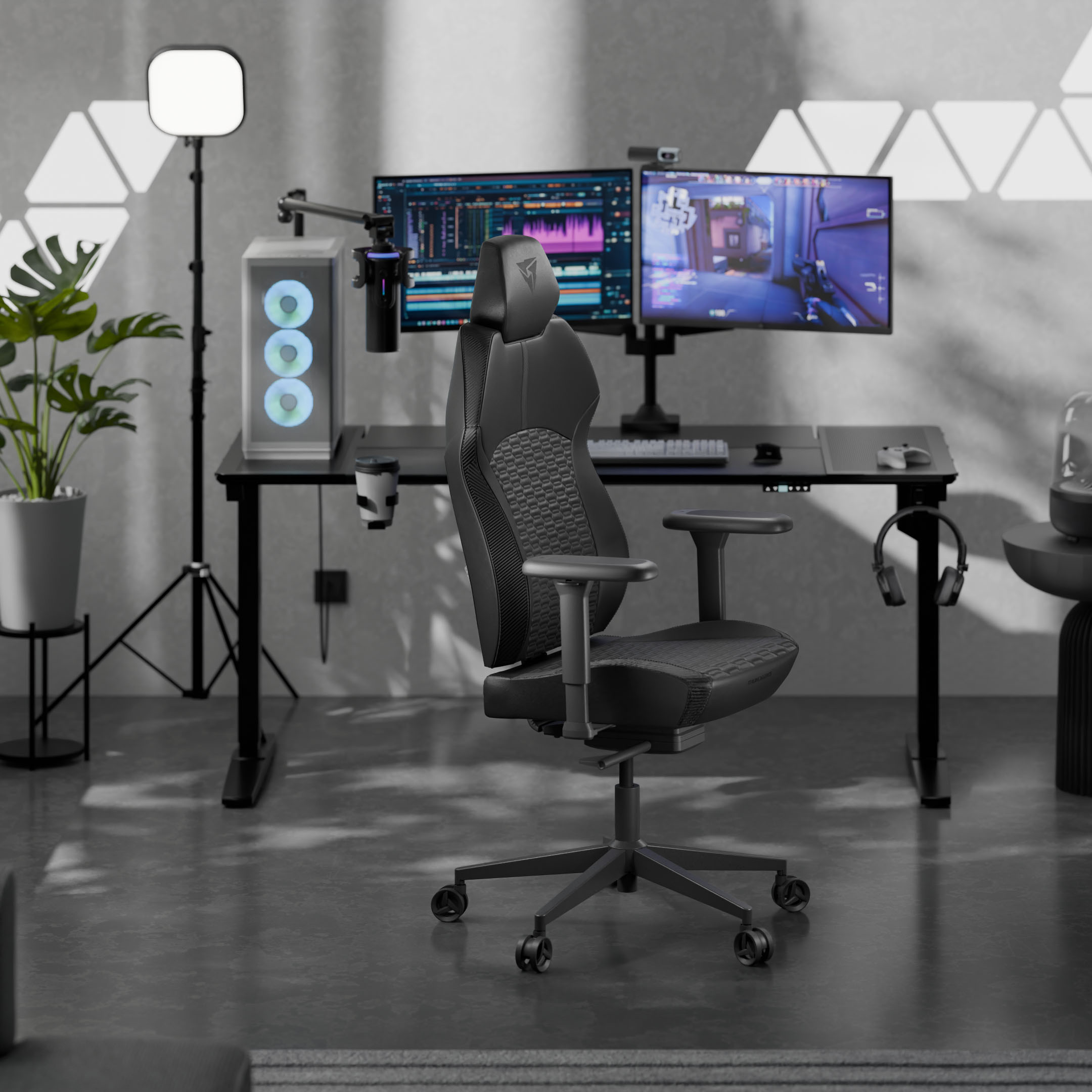 Ein schwarzer Gaming-Stuhl vor einem Schreibtisch mit zwei Monitoren, PC und Lampe.