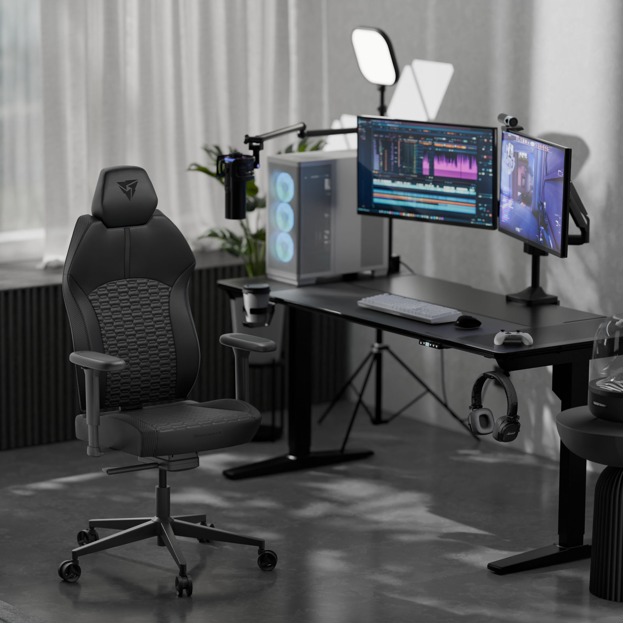 Ein schwarzer Gaming-Stuhl steht vor einem Schreibtisch mit Computern und Lichtern.