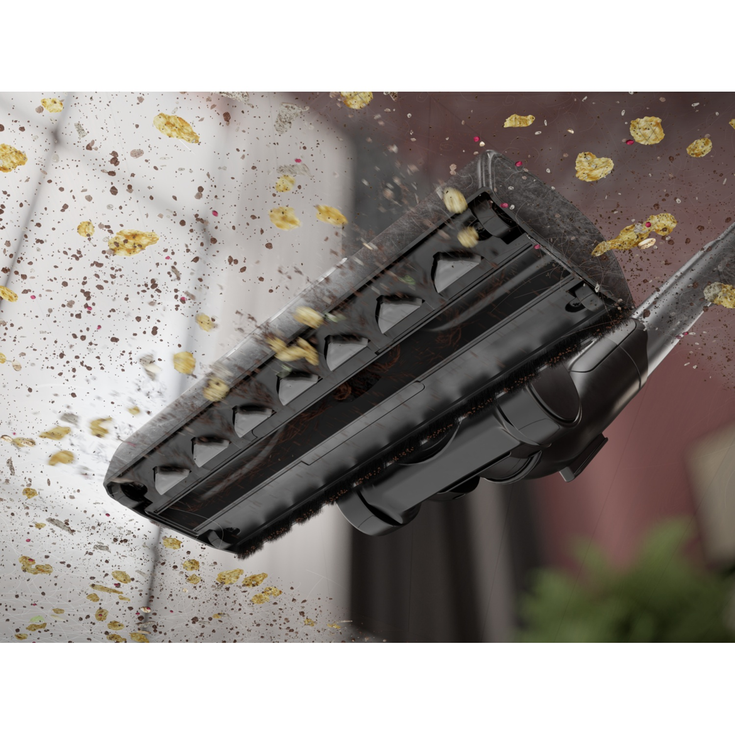 A black vacuum cleaner head is sucking up scattered debris.