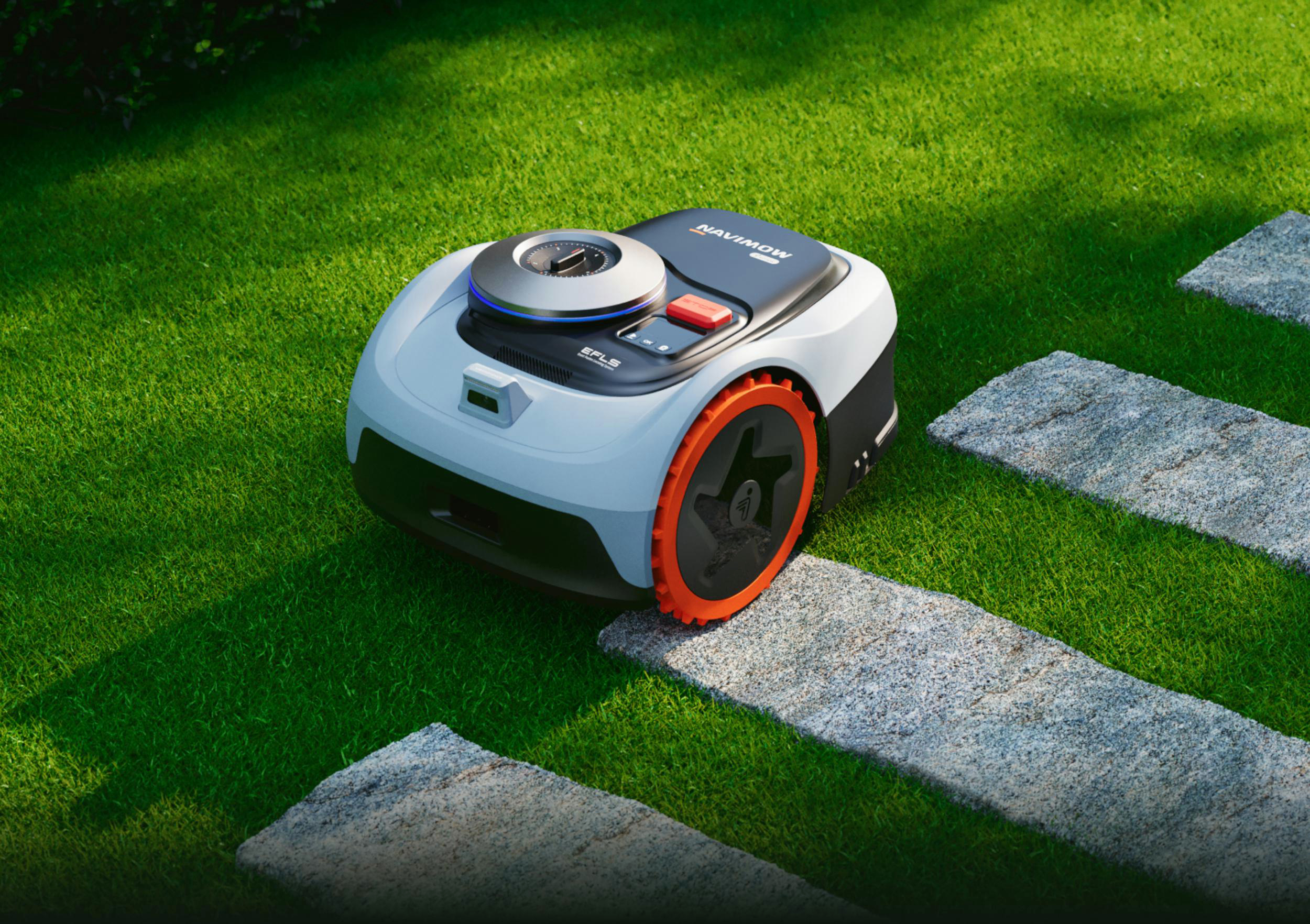 Ein autonomer Rasenmähroboter auf einem grünen Rasen mit Steinplatten.