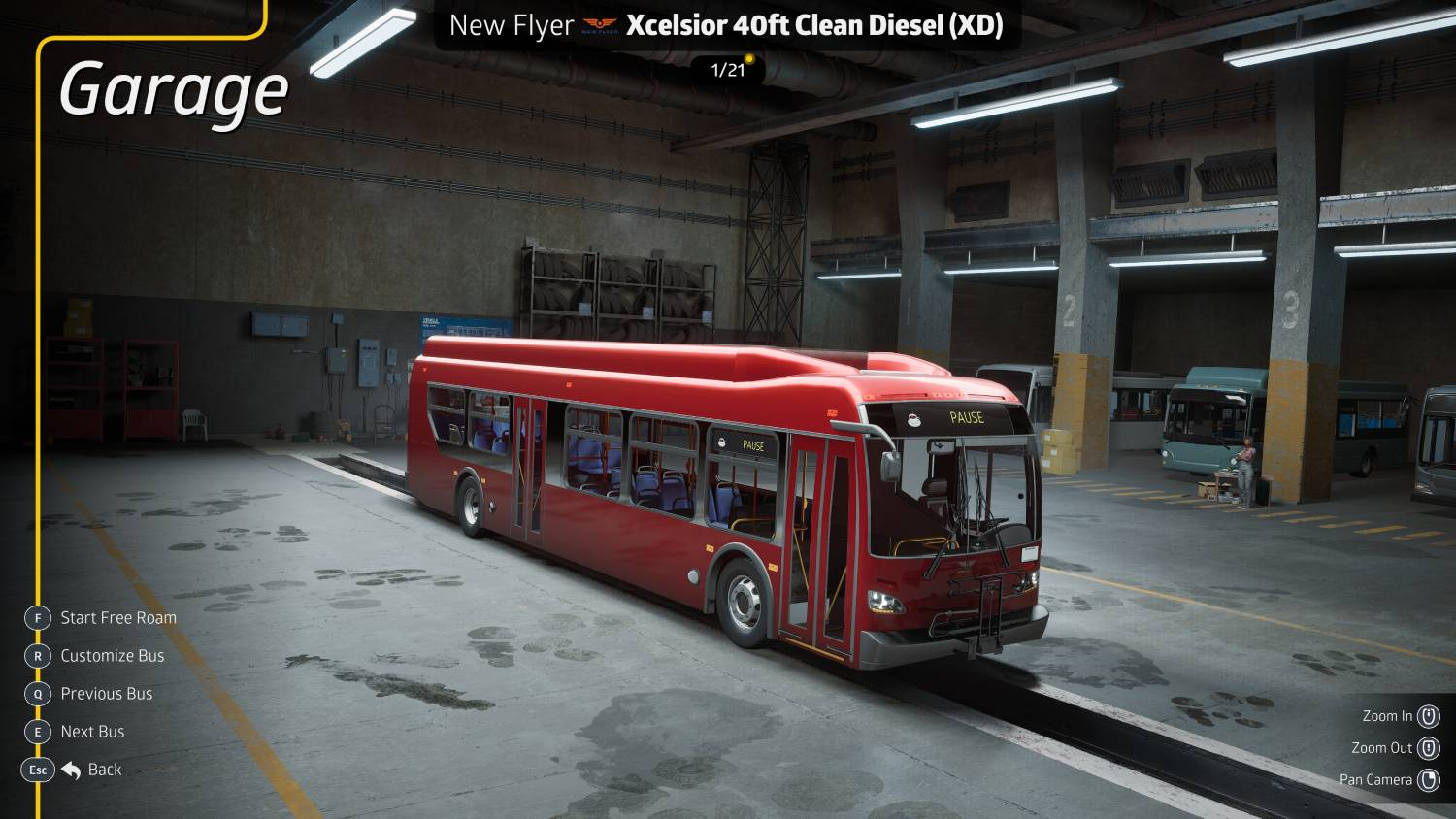 Un autobús rojo está aparcado en un garaje con otros autobuses al fondo.