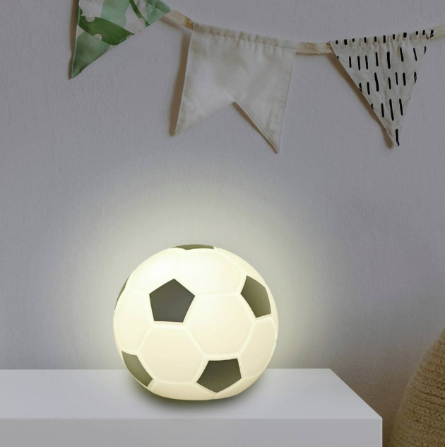 Ein leuchtender Ball im Fußball-Design steht auf einem weißen Regal, darüber eine Girlande.