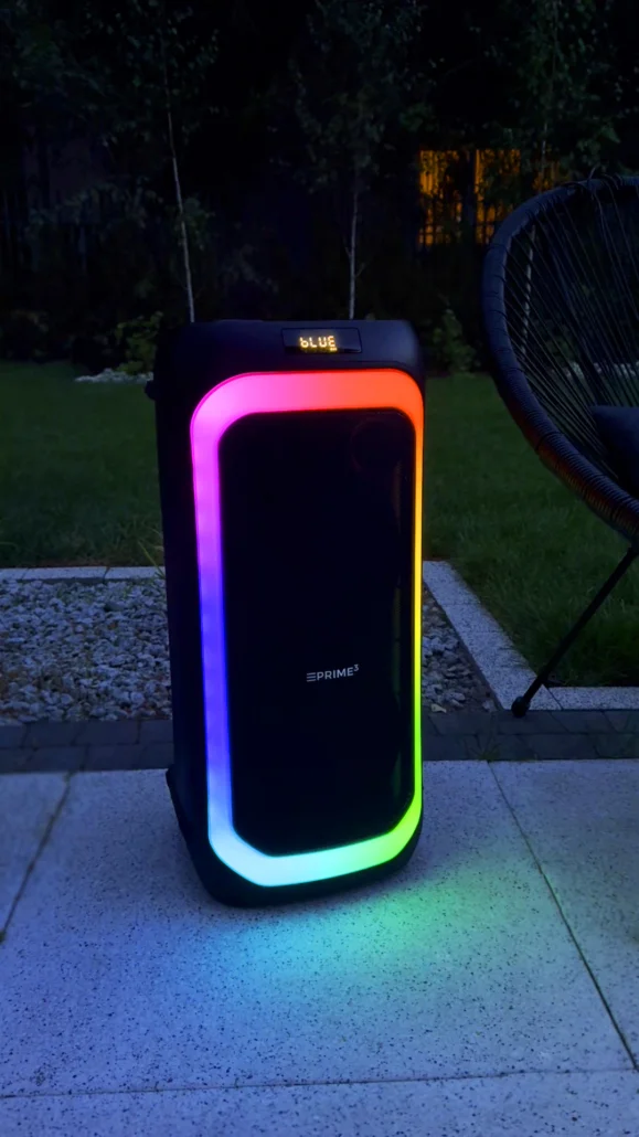 Czarny głośnik z kolorowymi światłami stoi na zewnątrz na tarasie.