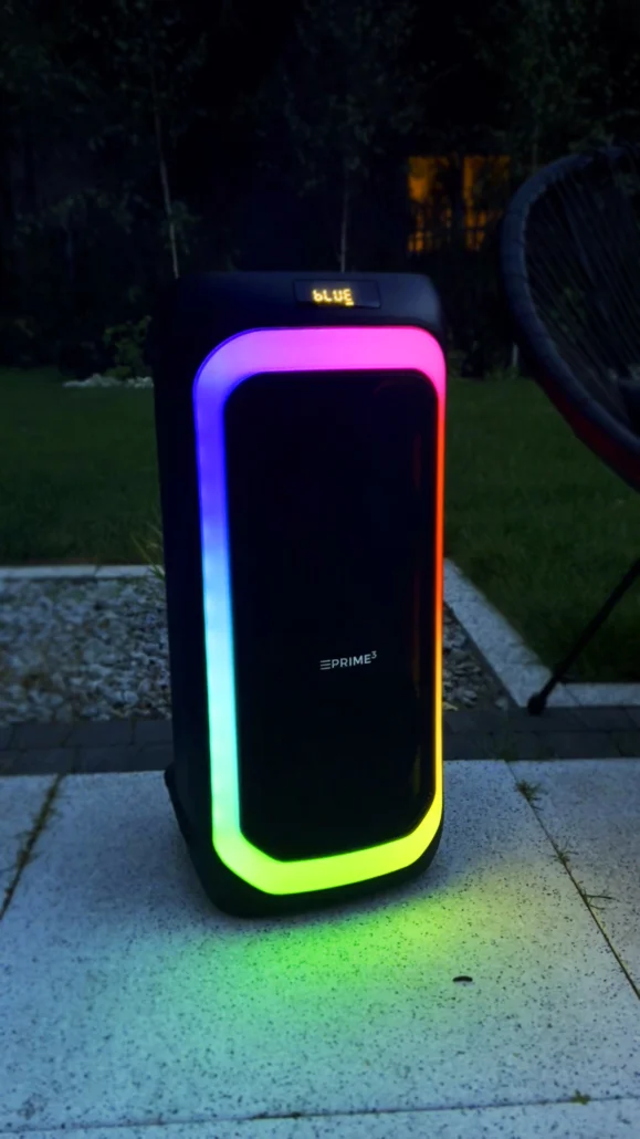 Czarny głośnik z kolorowymi światłami stoi na zewnątrz na tarasie.