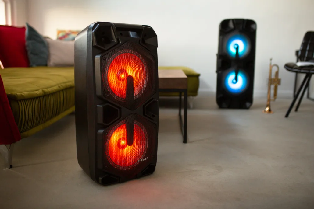 Dwa głośniki z czerwonymi i niebieskimi światłami stoją w pokoju.