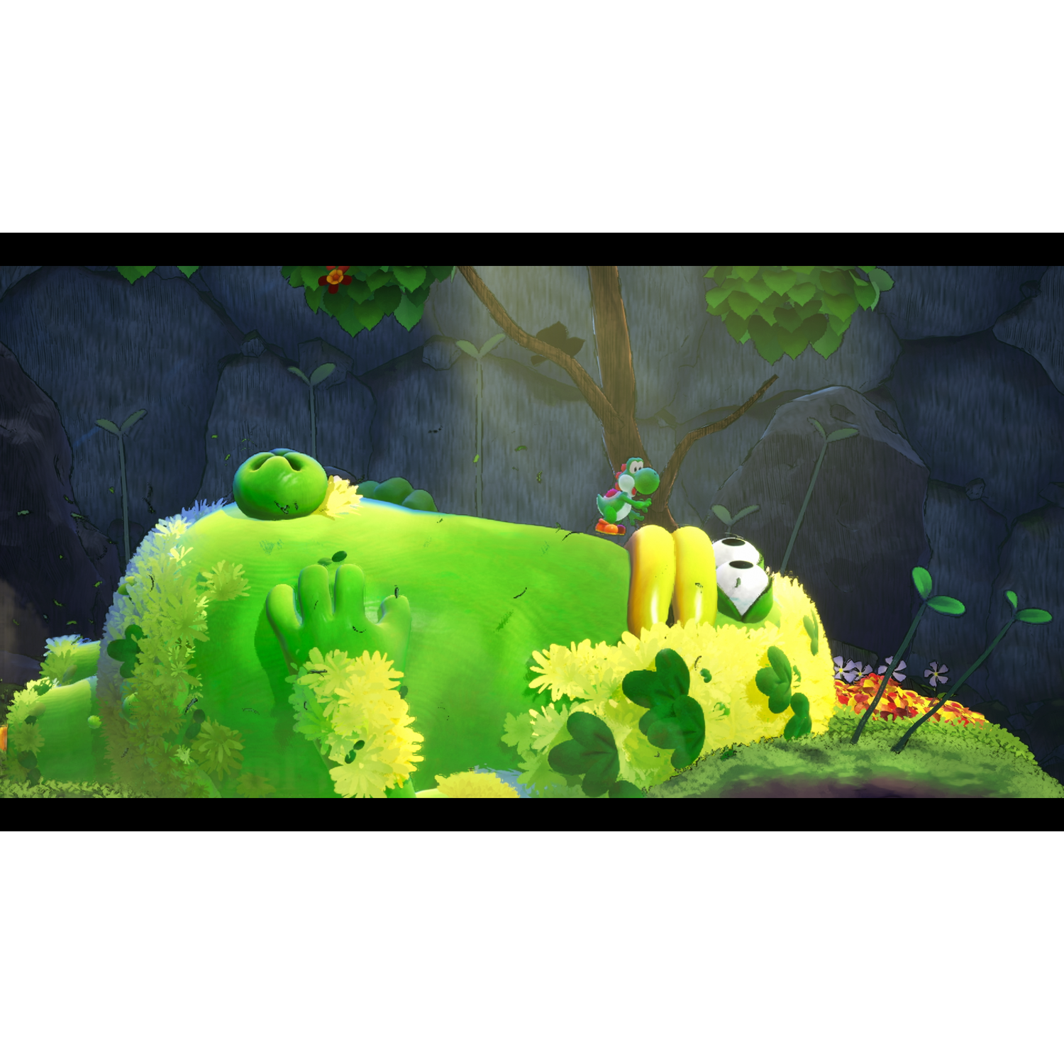 A green Yoshi stands on a giant green creature covered in flowers and grass.