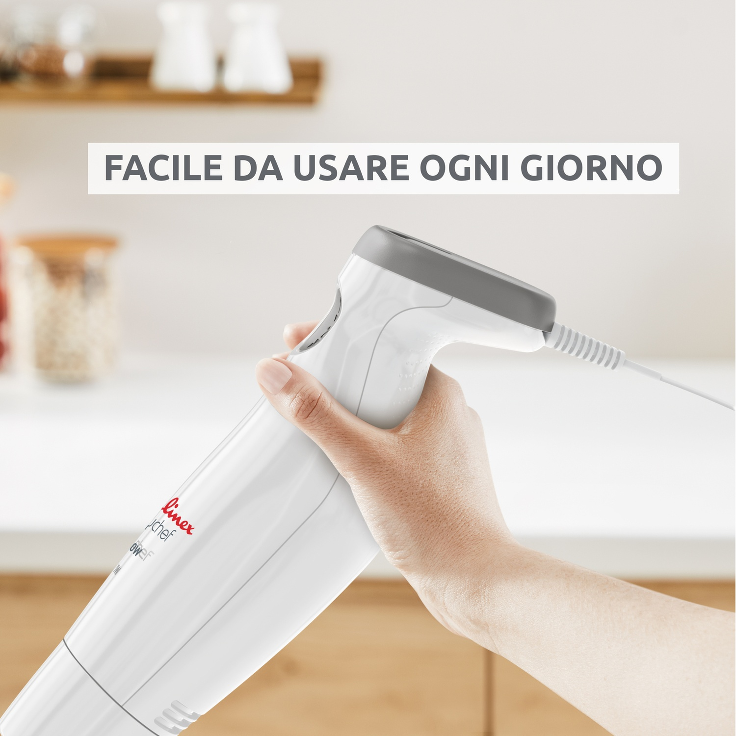 Una mano tiene un frullatore a immersione bianco con manico grigio. Testo: Facile da usare ogni giorno.