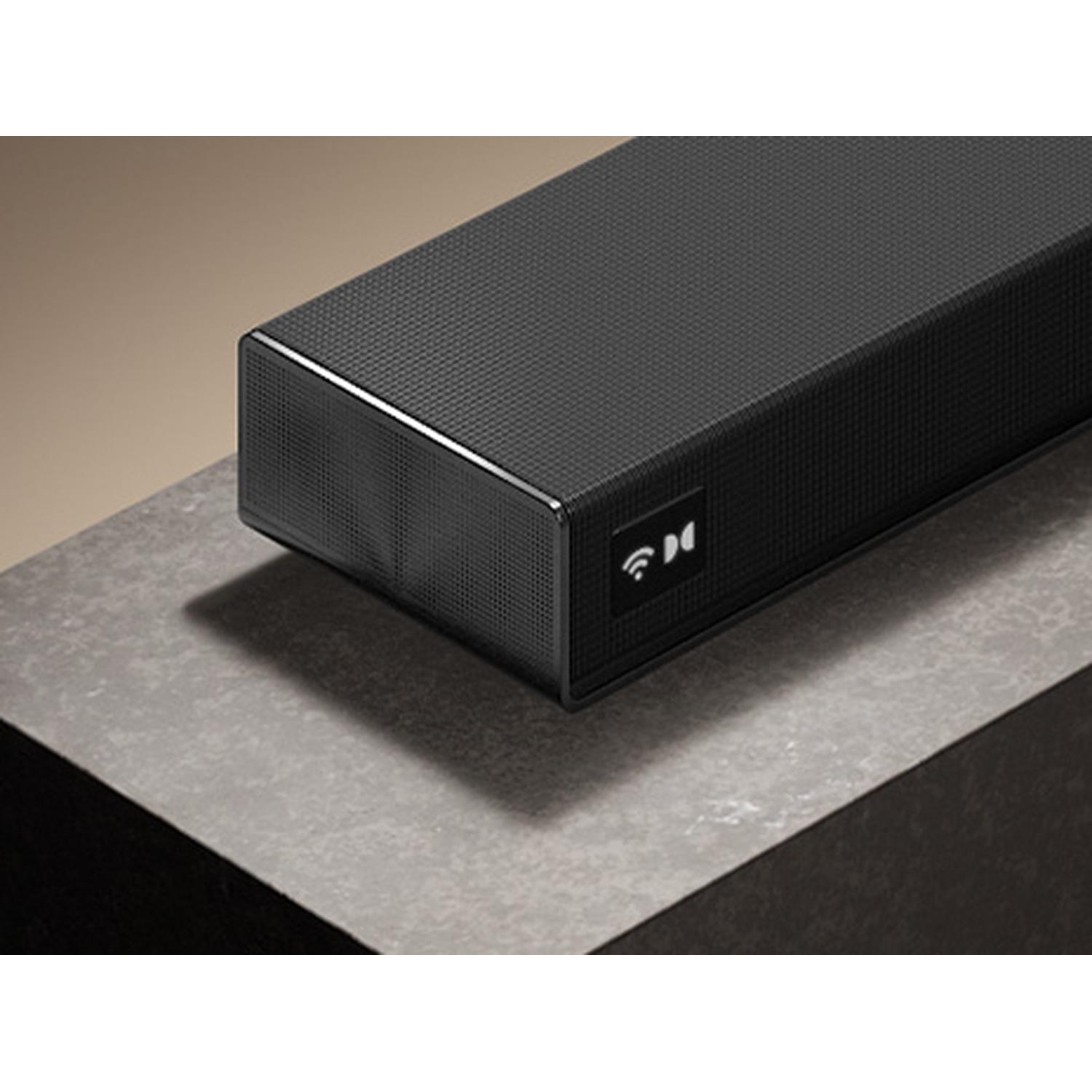 Black soundbar with Dolby Atmos symbol on a stone surface.