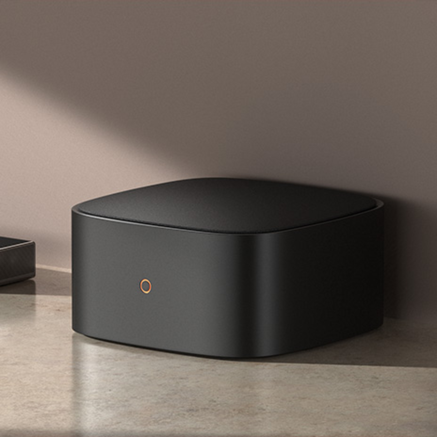 A black, cube-shaped device with an orange circle on its front.