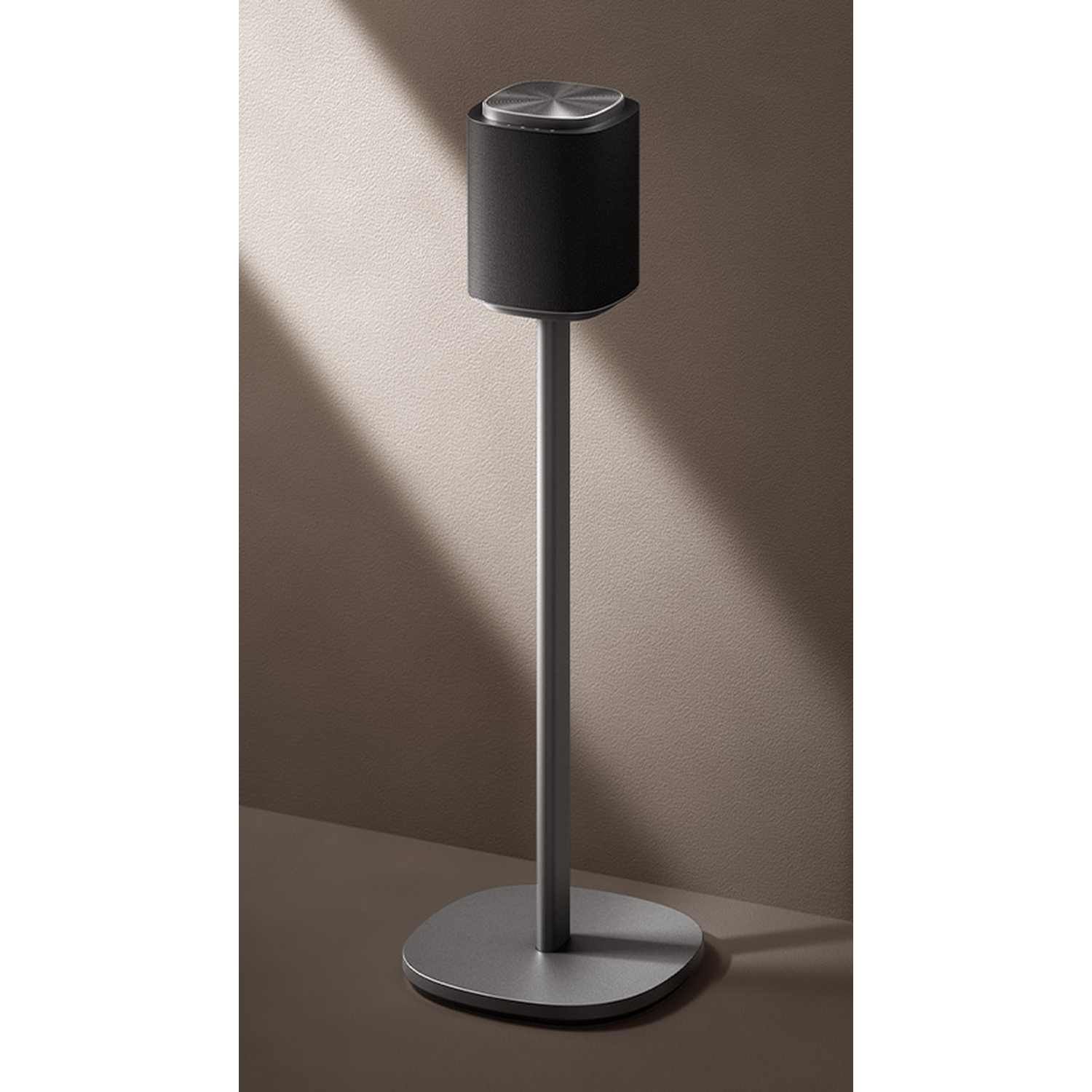 A cylindrical speaker sits on a sleek metal stand with a round base.