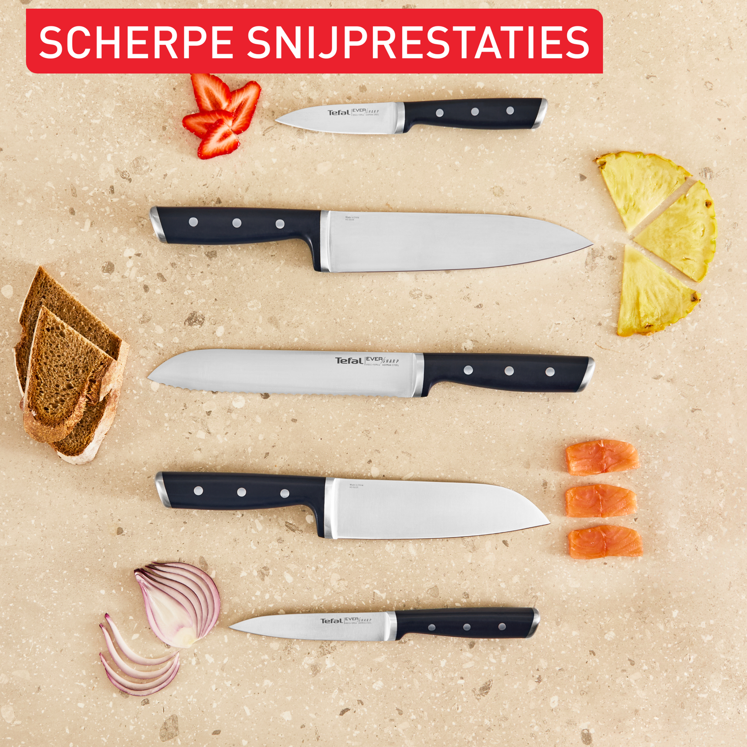 Knives with black handles, next to strawberries, bread, pineapple, salmon, and onions.