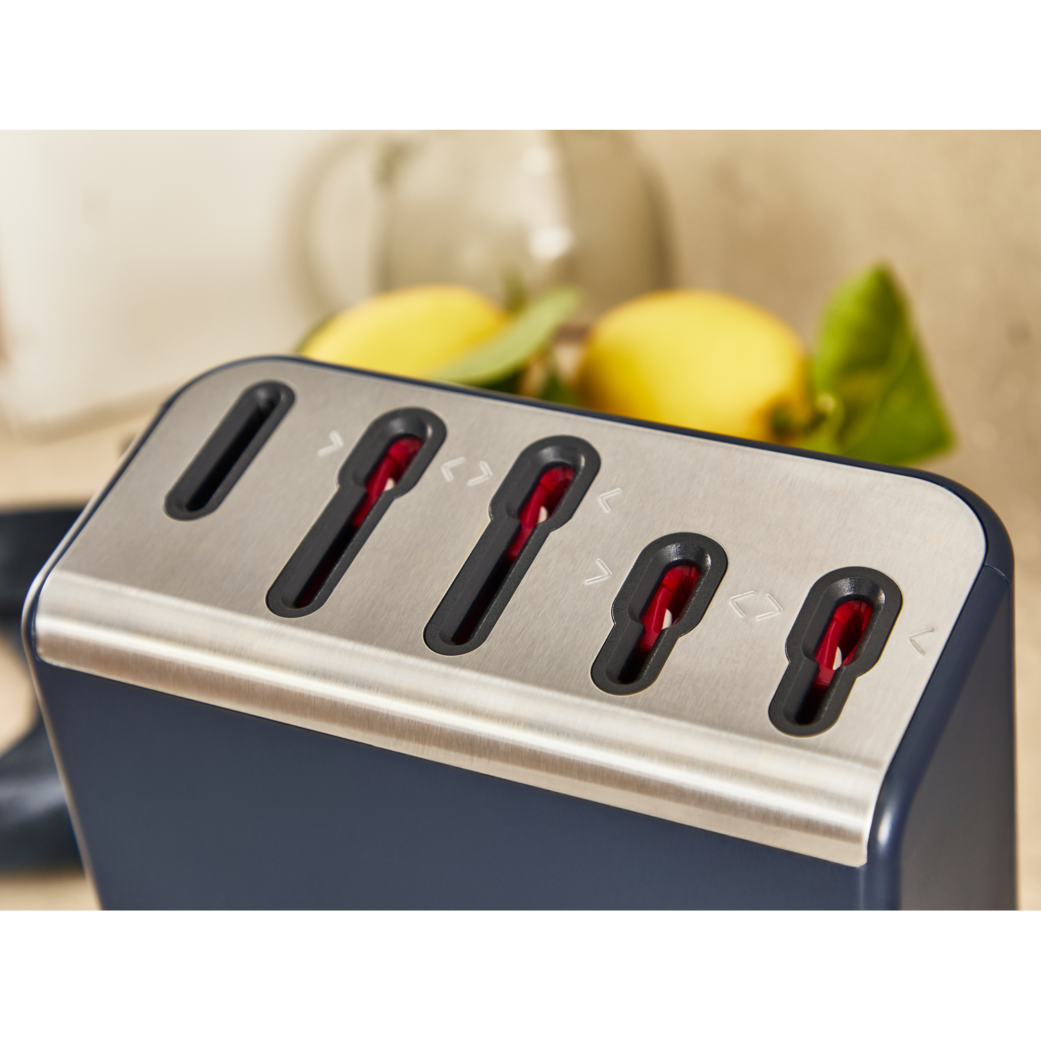 A dark knife block with a stainless steel top and red inserts.