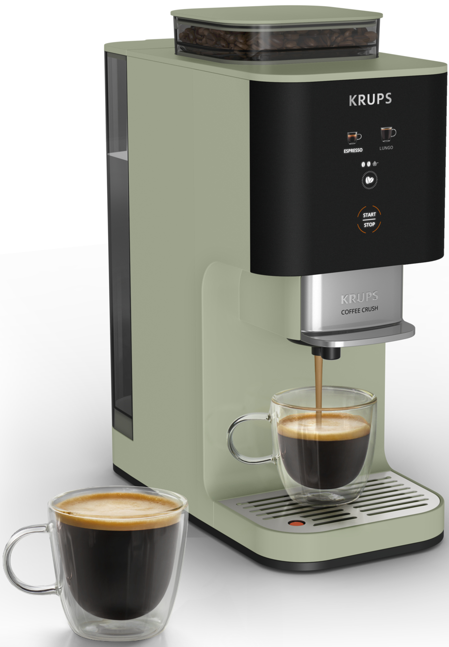Eine grüne Krups Kaffeemaschine brüht Kaffee in ein Glas. Zwei Tassen sind sichtbar.
