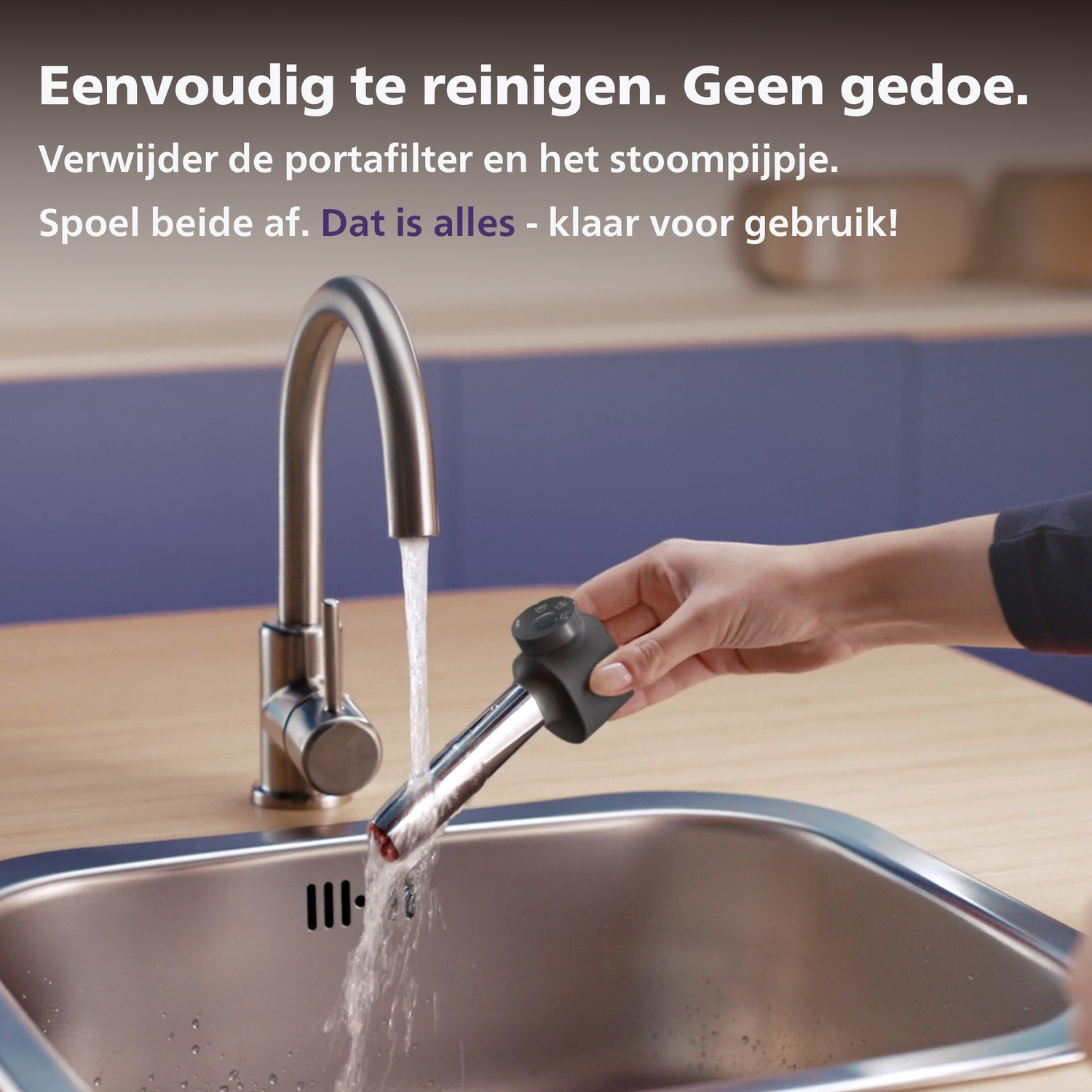 A hand rinses a coffee filter holder and steam wand under running water in a sink.