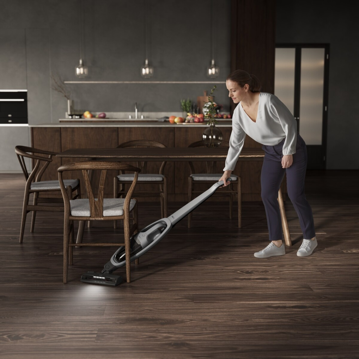 Woman vacuums wooden floor in dining room with cordless vacuum cleaner.