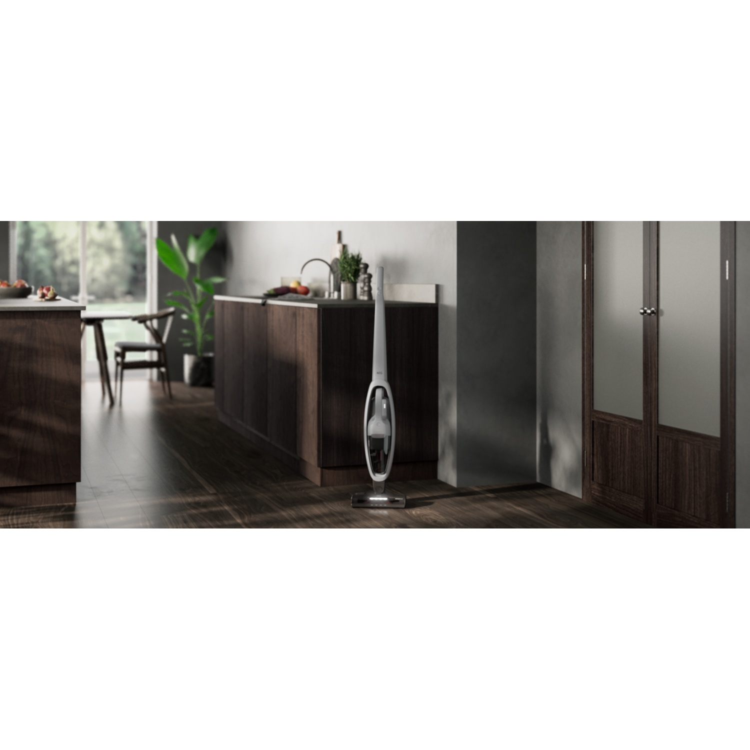 A white cordless vacuum stands in a modern kitchen with wooden floors.
