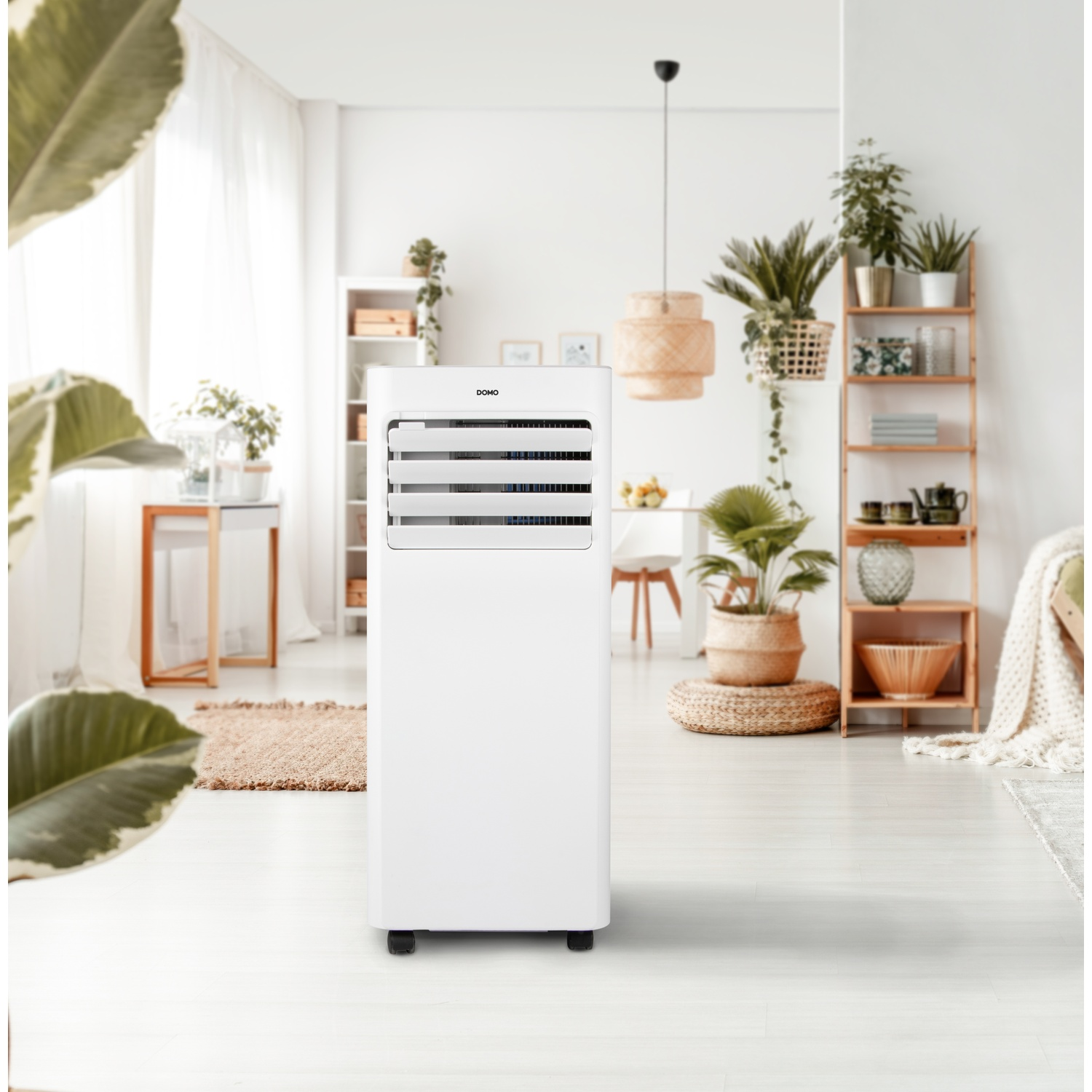 A white portable air conditioner stands in a bright, plant-filled living room with light wood accents.