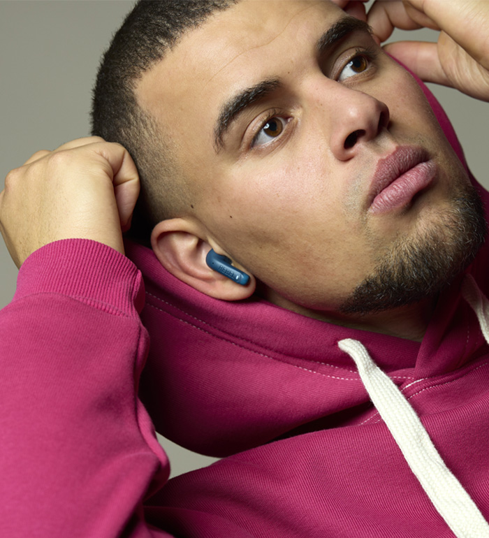 Ein Mann mit Kopfhörern und einem pinken Hoodie schaut nach oben.