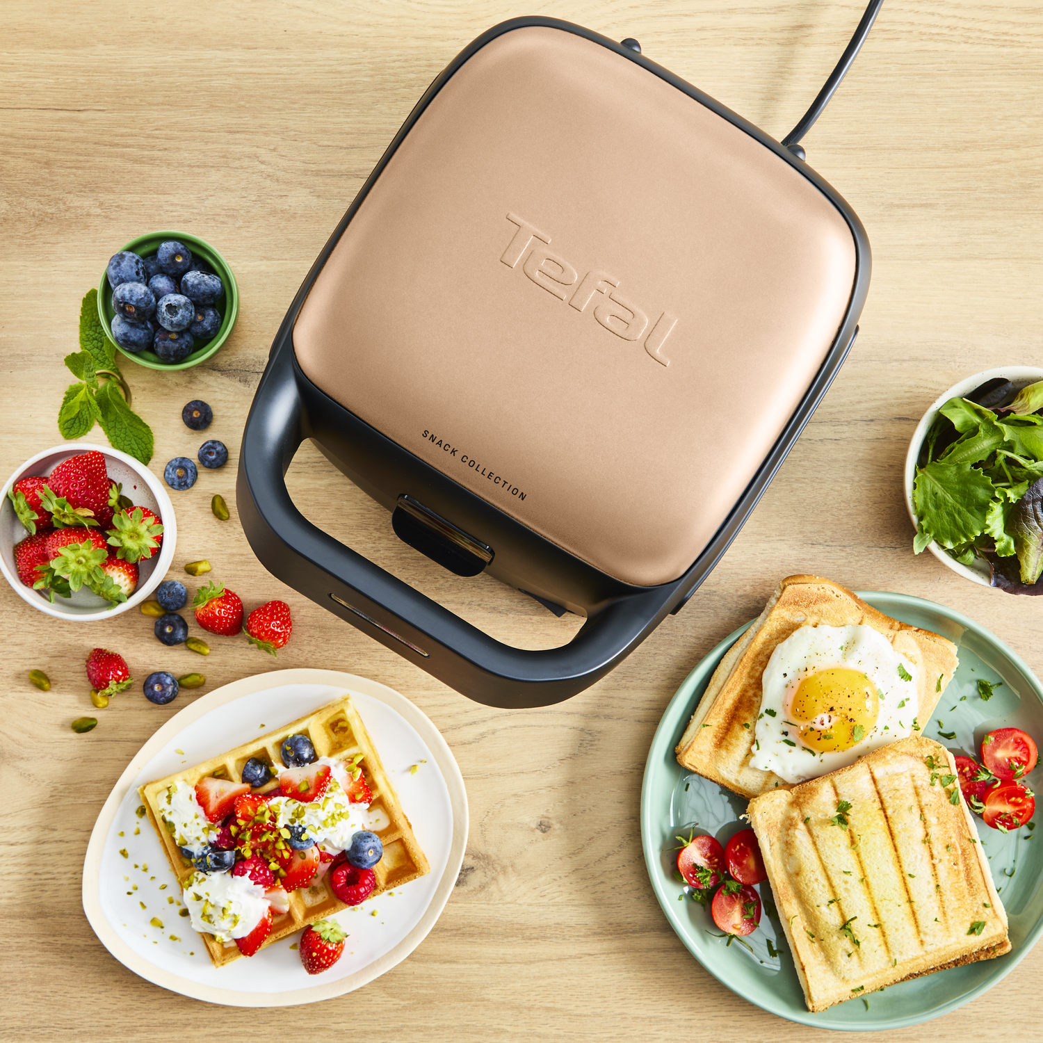 Tefal snack maker with waffle, toast, and berries on a wooden table.