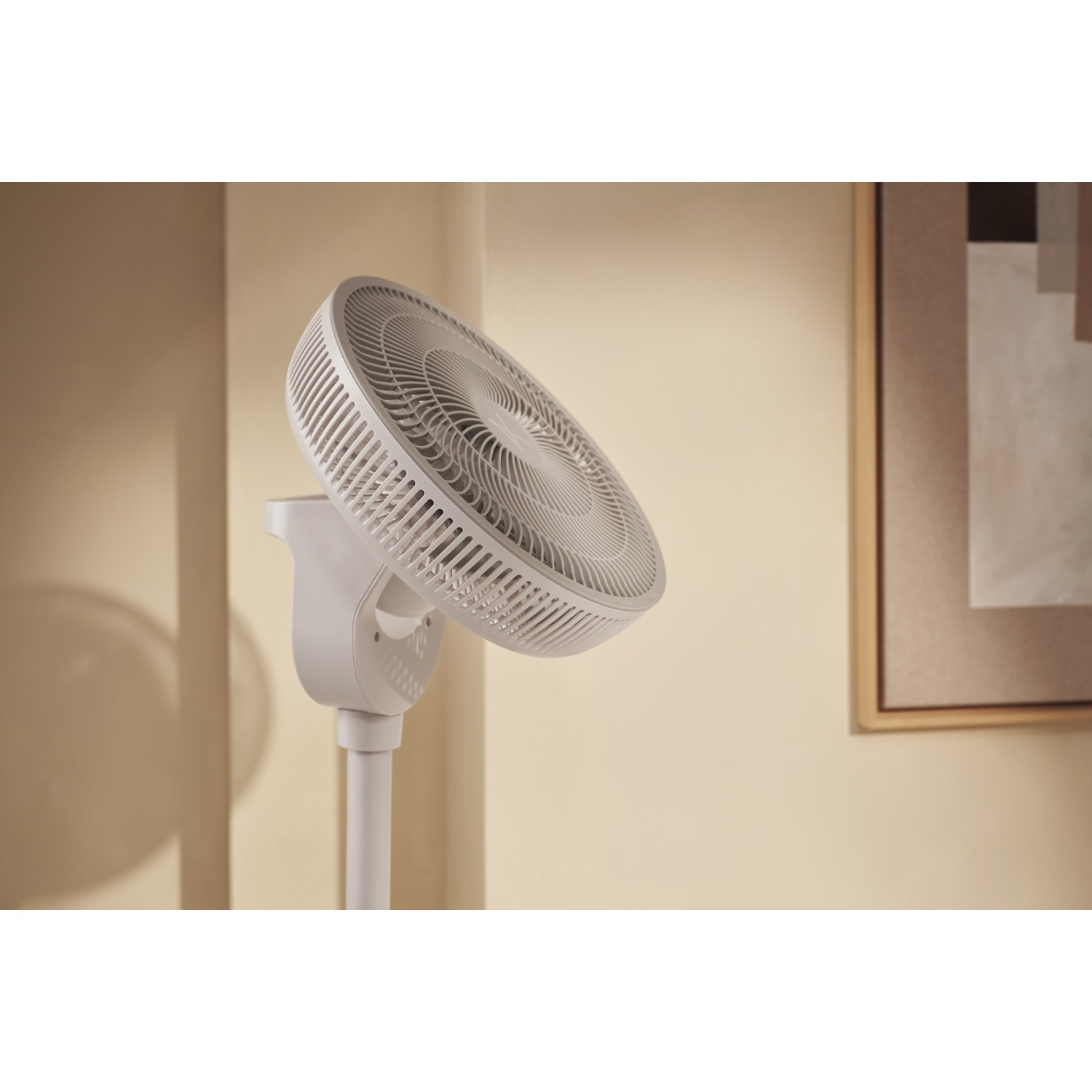 Un ventilateur blanc sur pied à tête ronde est montré à l'intérieur.