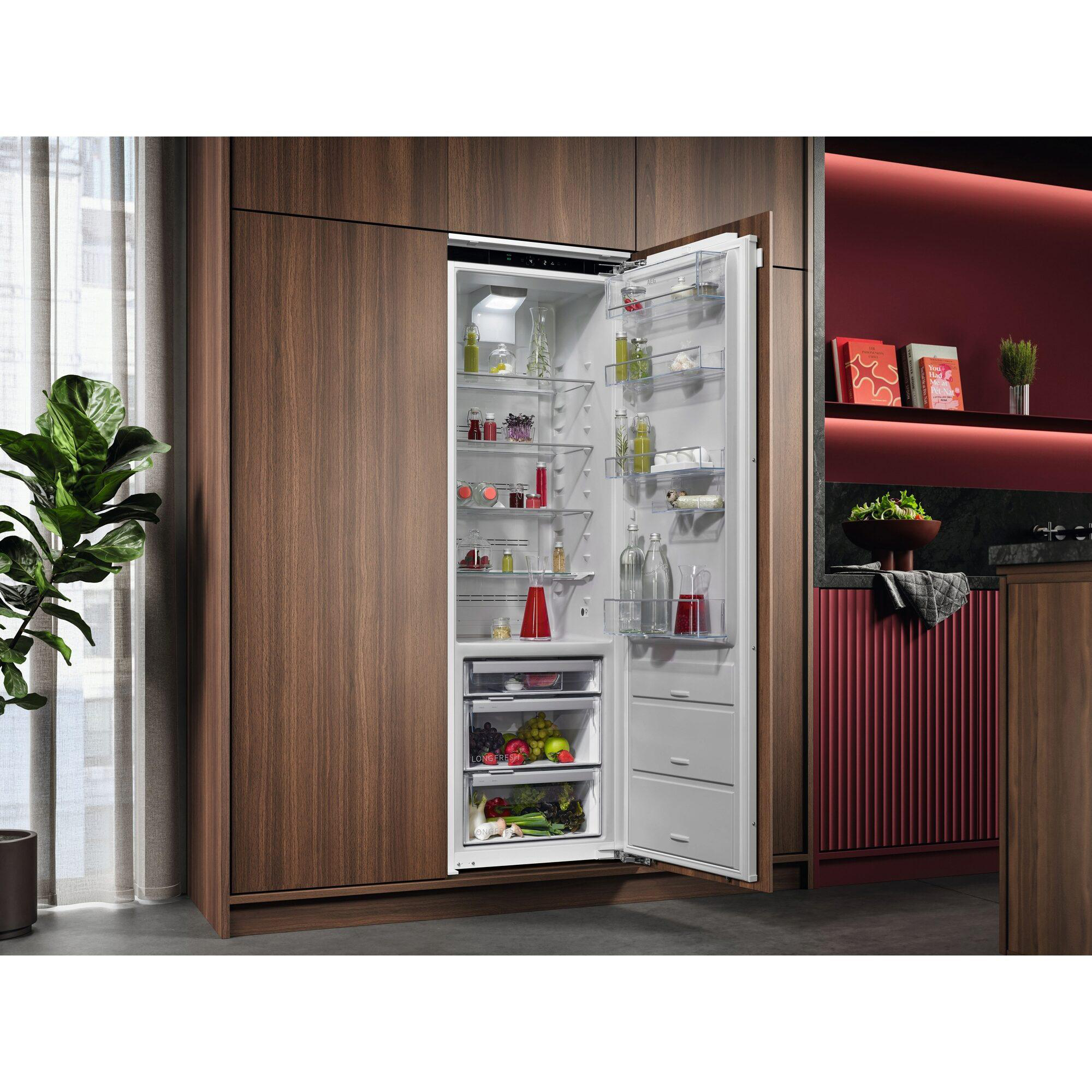 Offener Kühlschrank mit Lebensmitteln, Obst und Flaschen auf den Regalböden.