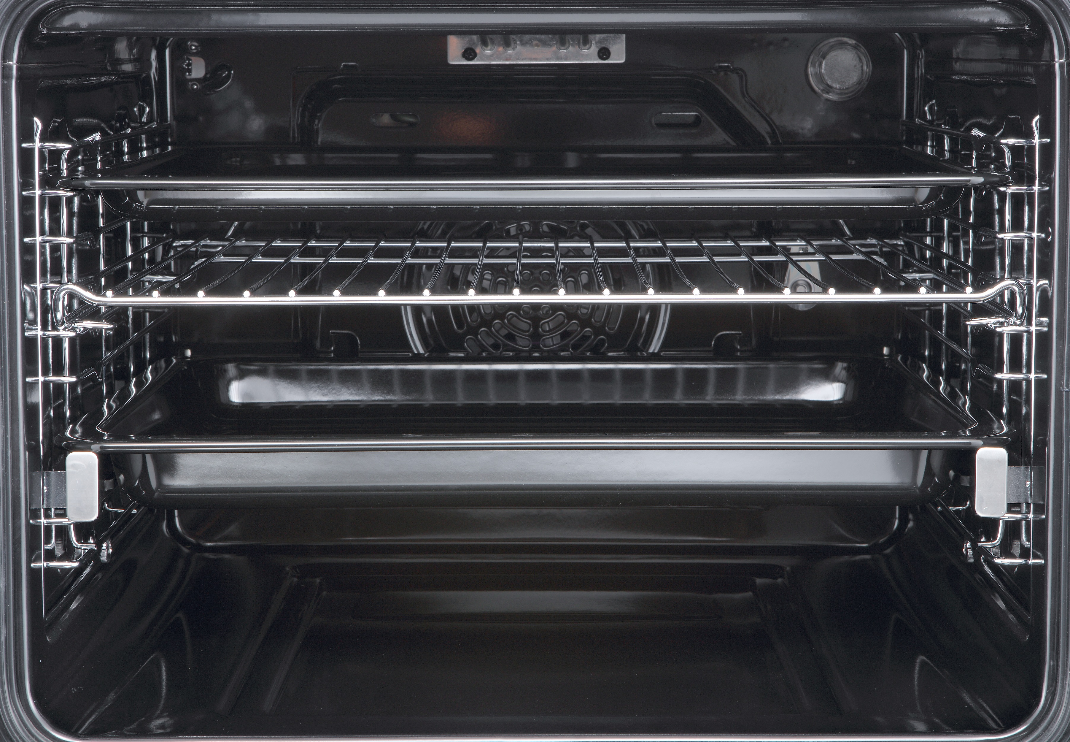 Interior de un horno negro vacío con tres rejillas metálicas y dos bandejas.